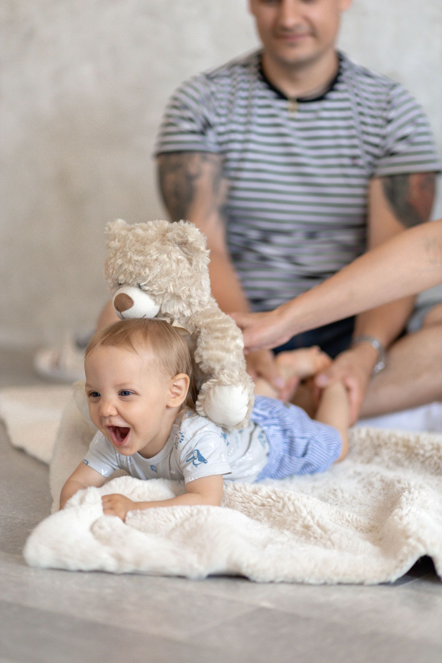 Candid family moment on white blanket during indoor photoshoot.