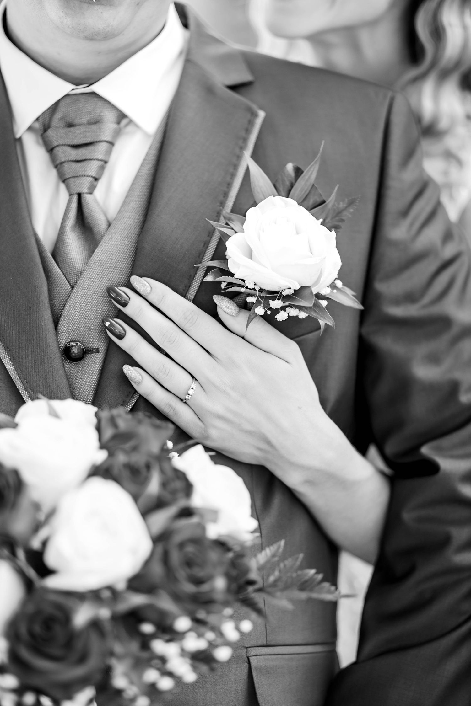 Black and white close-up of groomsmen in grey suits with white rose boutonnieres.