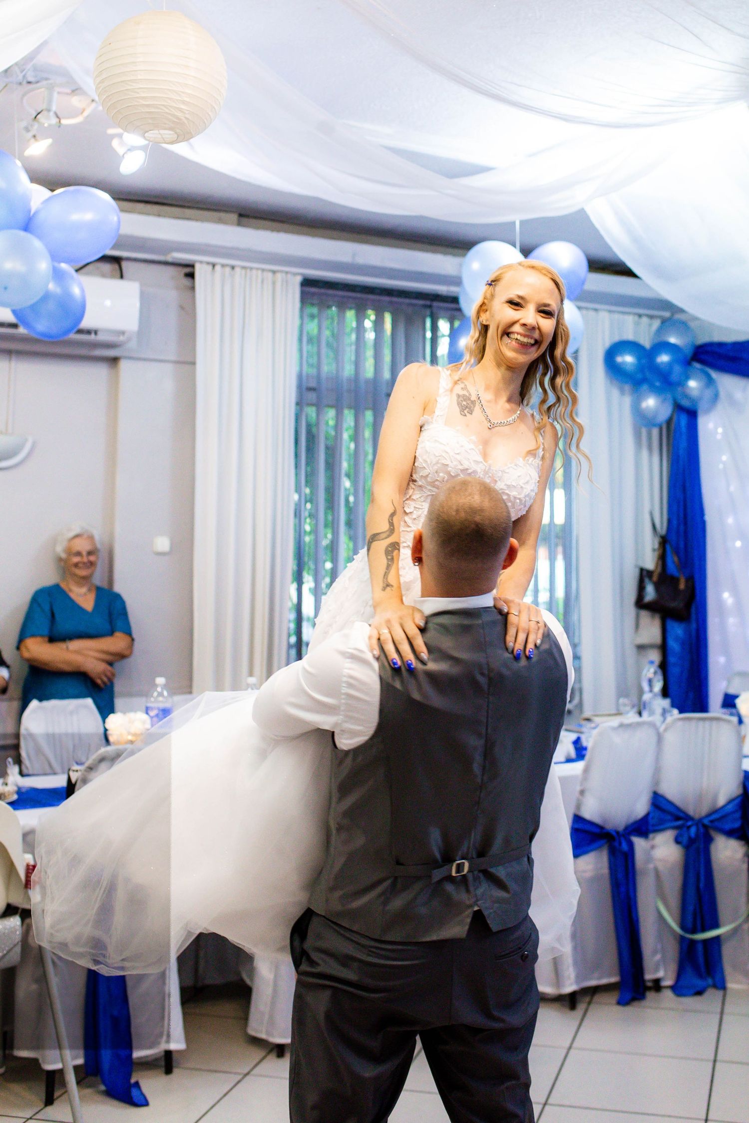 Couple dancing together at an elegant wedding reception decorated with white and blue balloons and lanterns.
