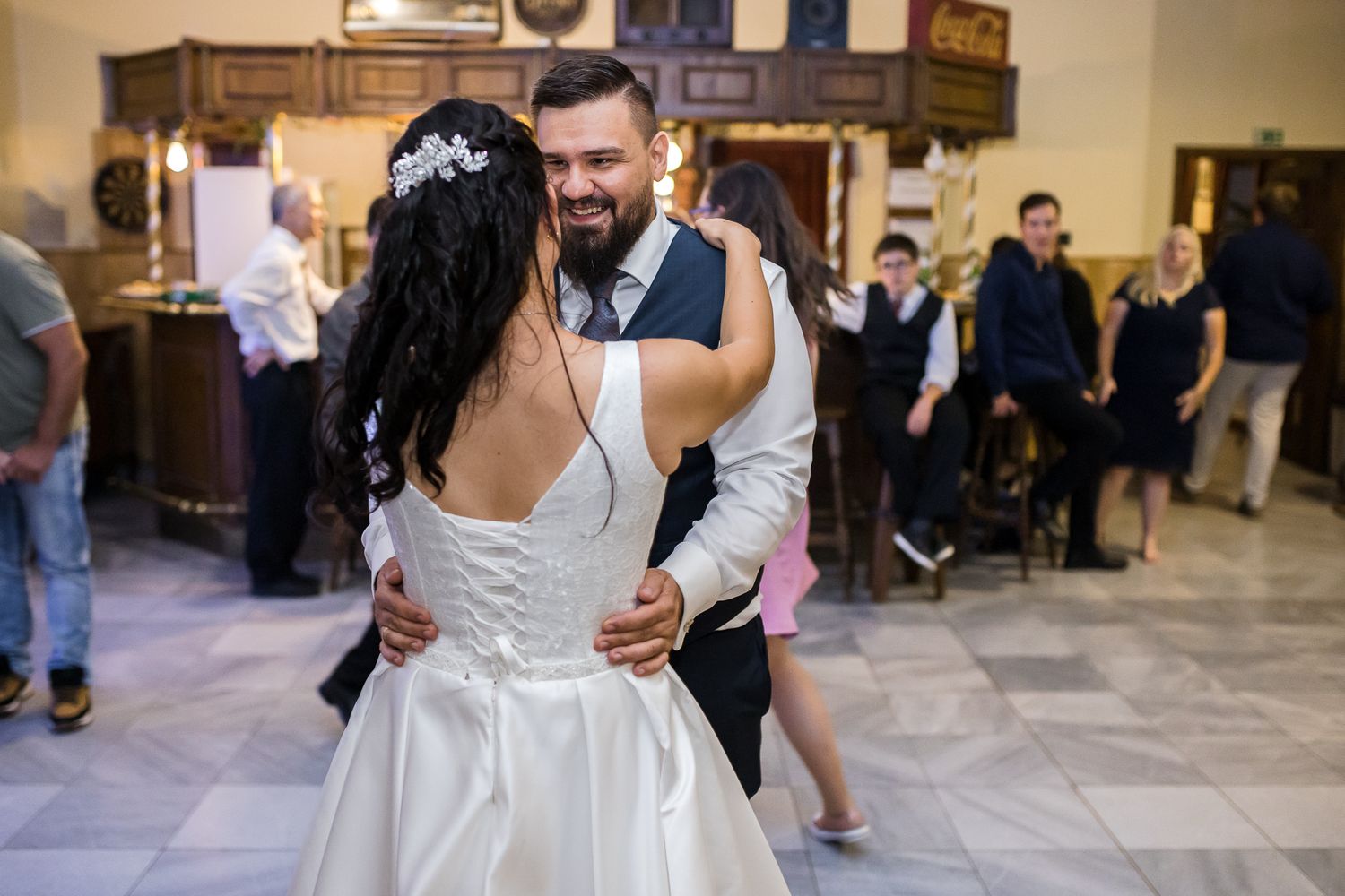 A happy couple in wedding attire embraces and dances together at their reception celebration.