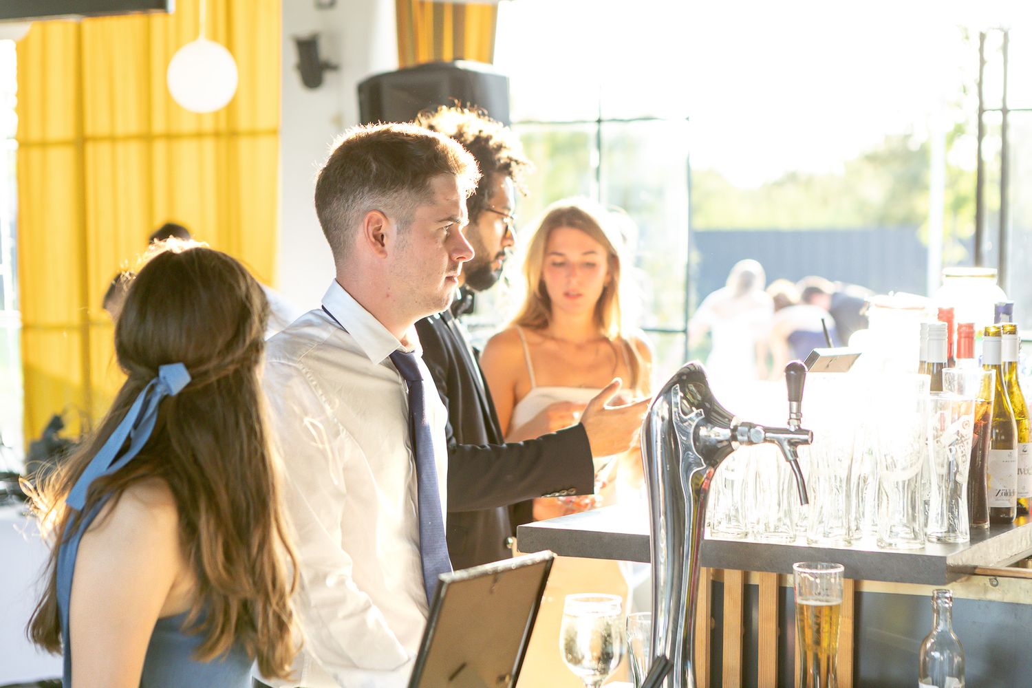 Wedding reception guests mingling in elegant indoor venue with warm lighting.