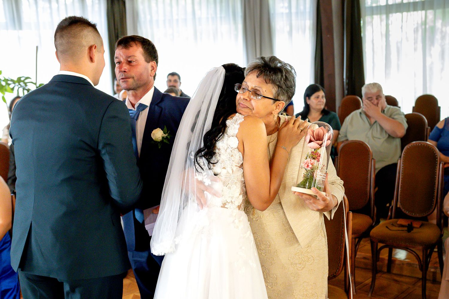 Wedding ceremony guests watch as couple shares their first kiss as newlyweds during intimate indoor celebration.