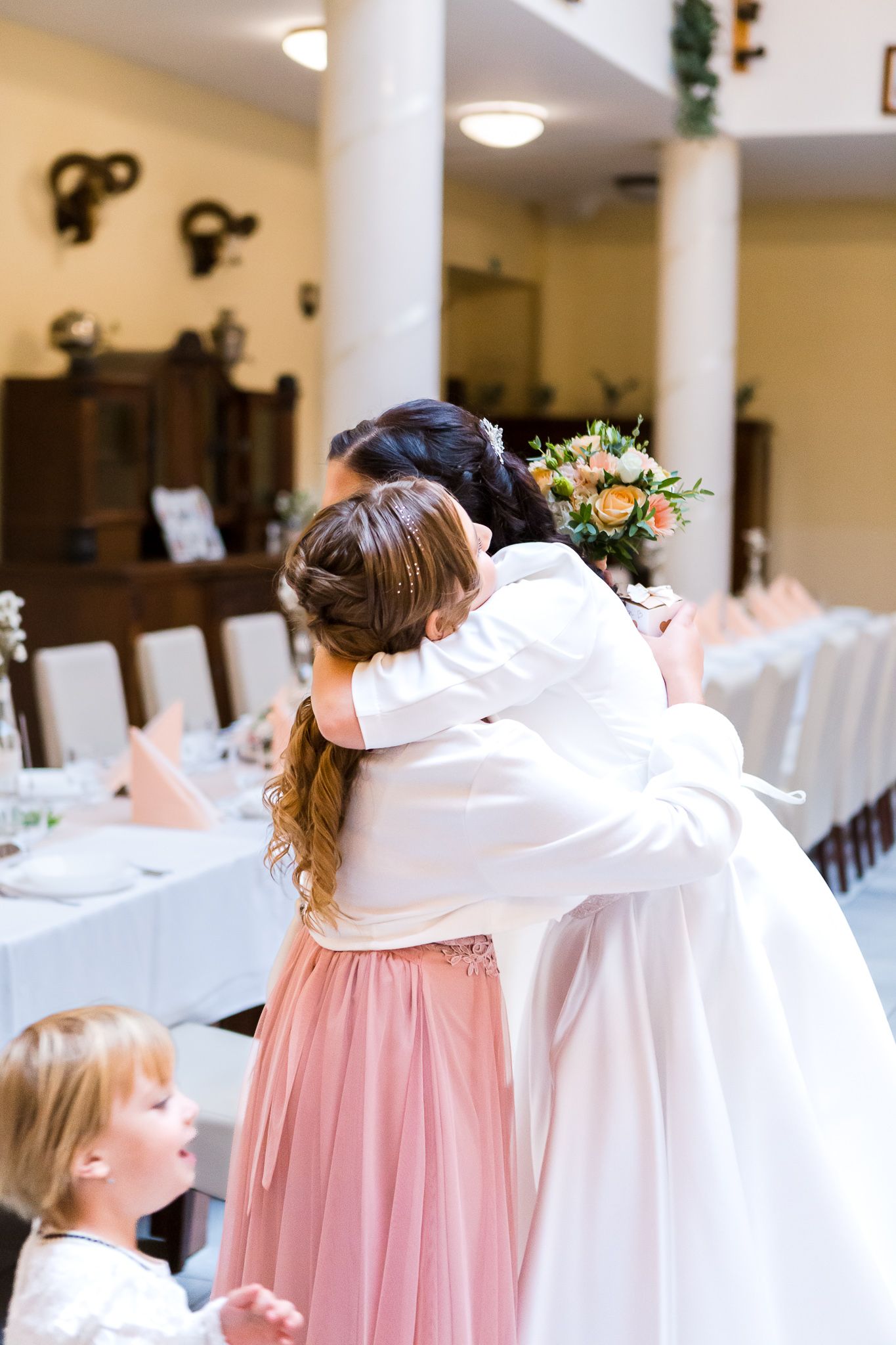 Bridesmaids in pink tulle skirts and white tops stand in a line at an elegant wedding reception venue.