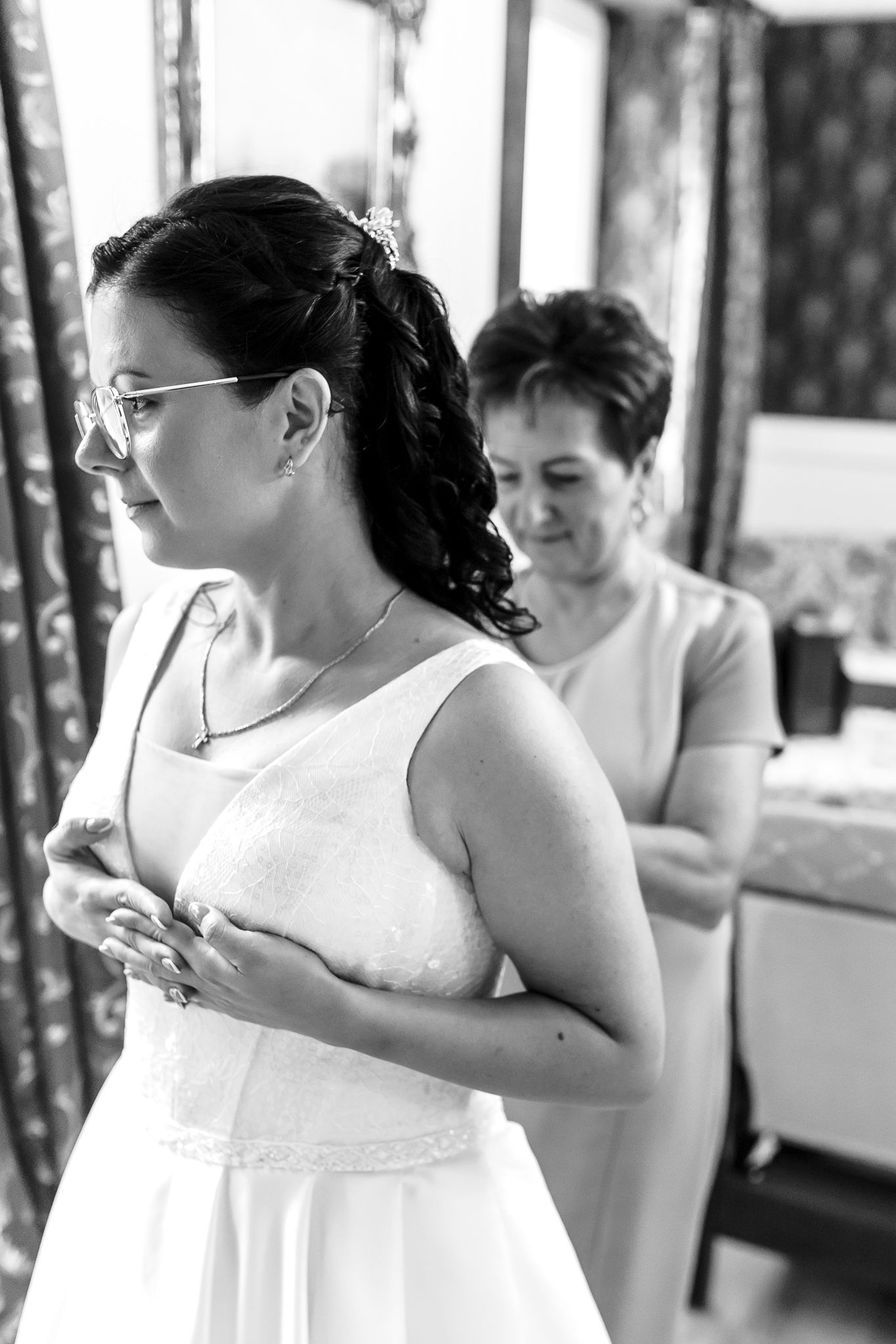 Black and white photo of bridesmaids in white dresses preparing for a wedding celebration.