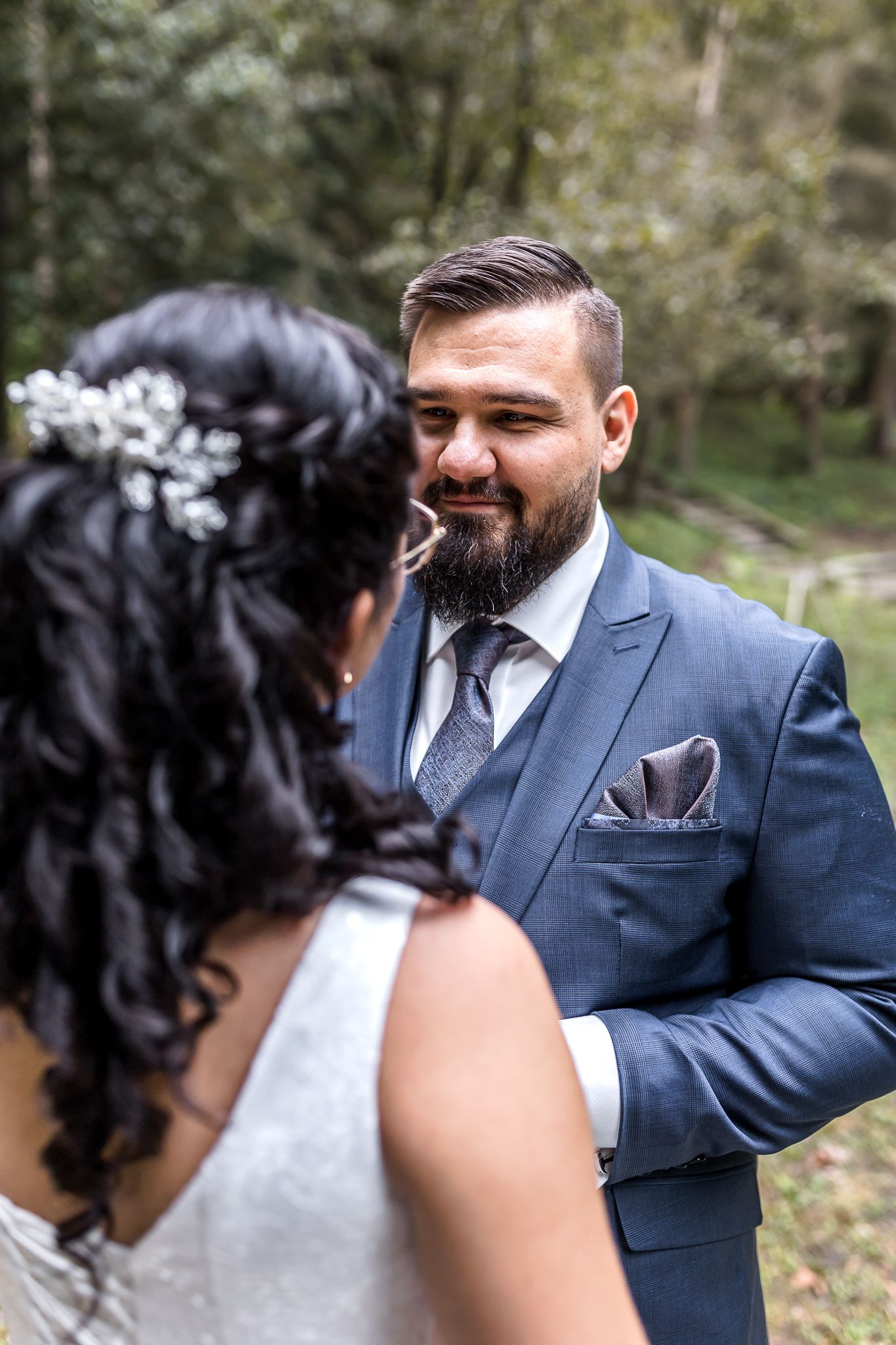 A couple in wedding attire share an intimate moment outdoors in a garden setting.