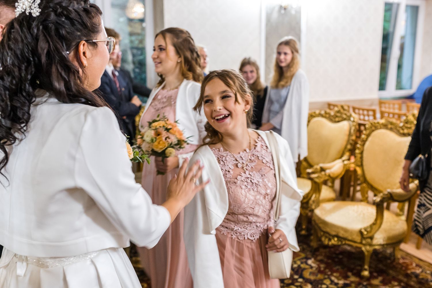 A bride and bridesmaids in pink dresses share emotional moments during a wedding celebration.