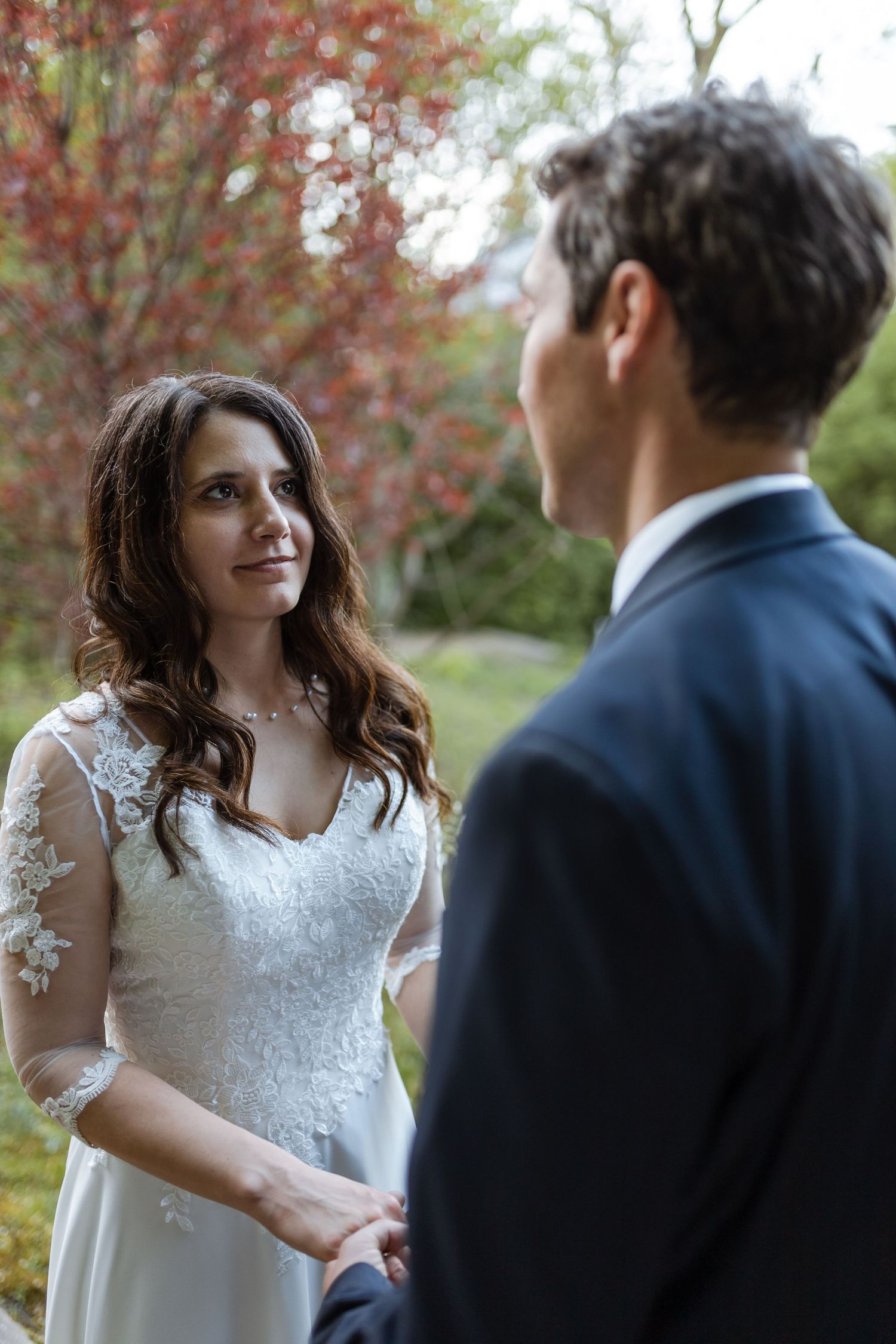 A bride and groom share tender moments during their autumn wedding photoshoot with fall foliage in the background.