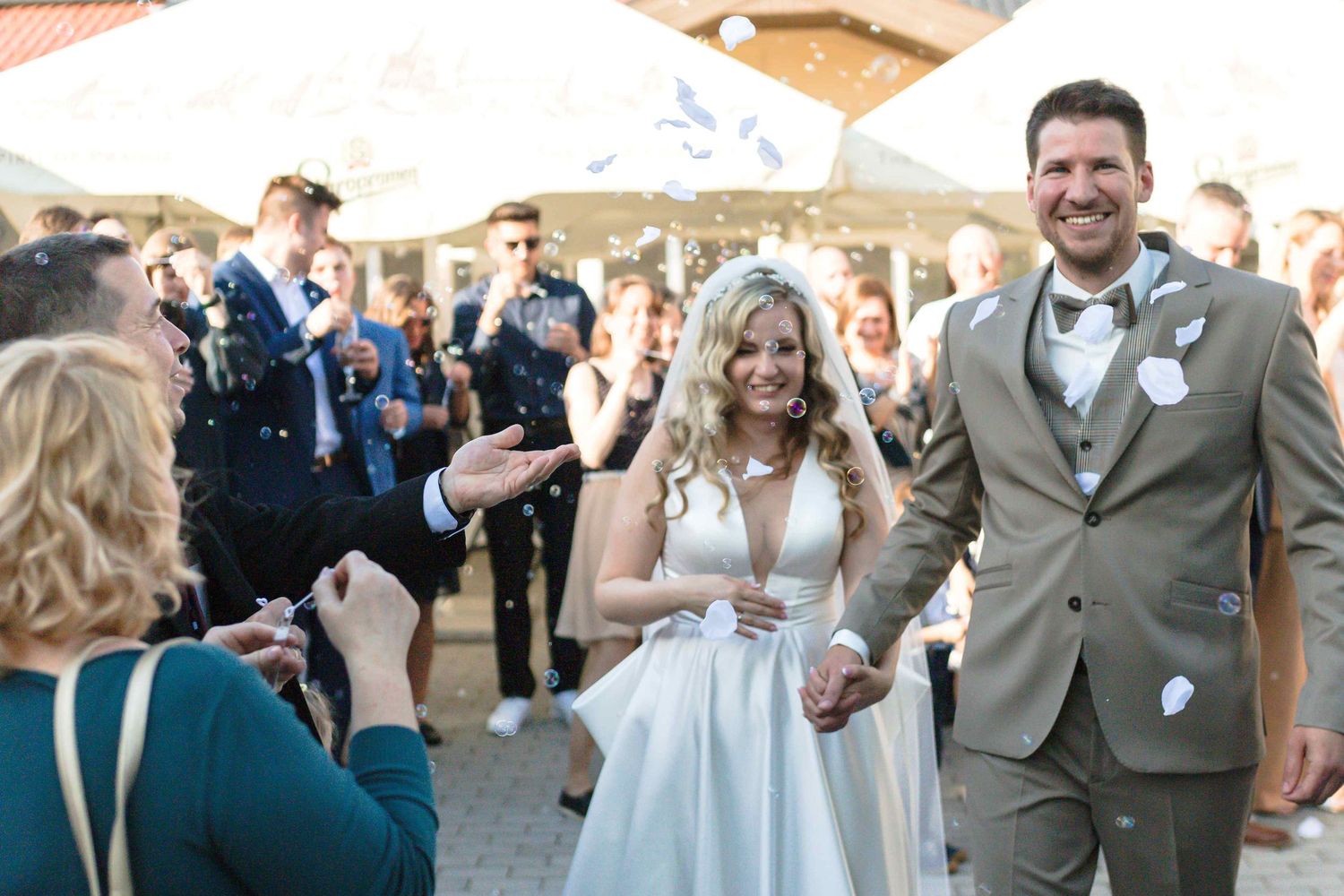 Wedding guests celebrate and dance together during an outdoor reception on a sunny day.