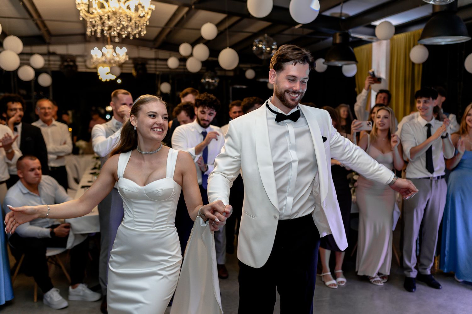 Couples dancing together at an elegant wedding reception with decorative lighting.