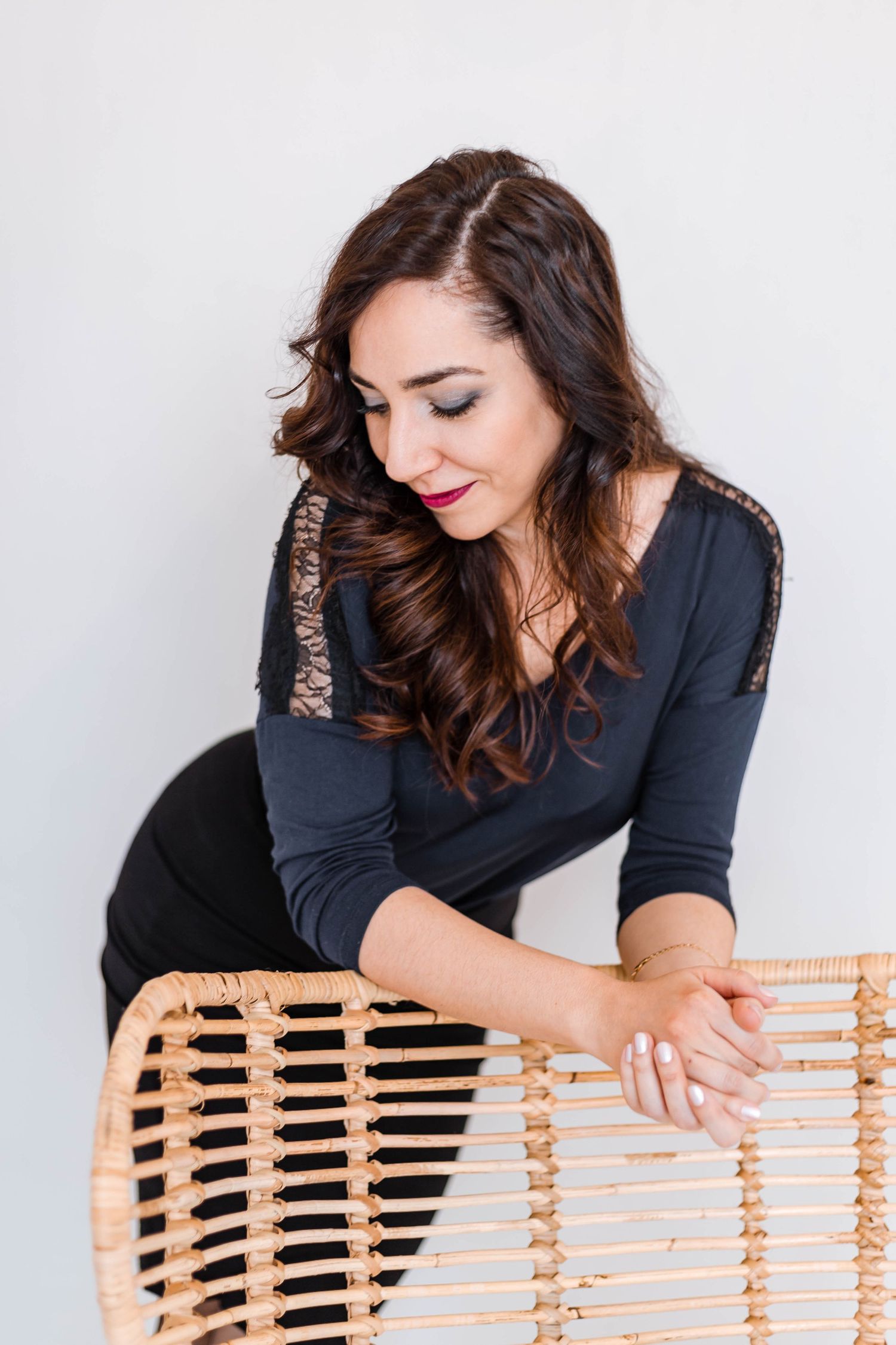 Creative pose with wooden chair showing professional style in dark outfit.