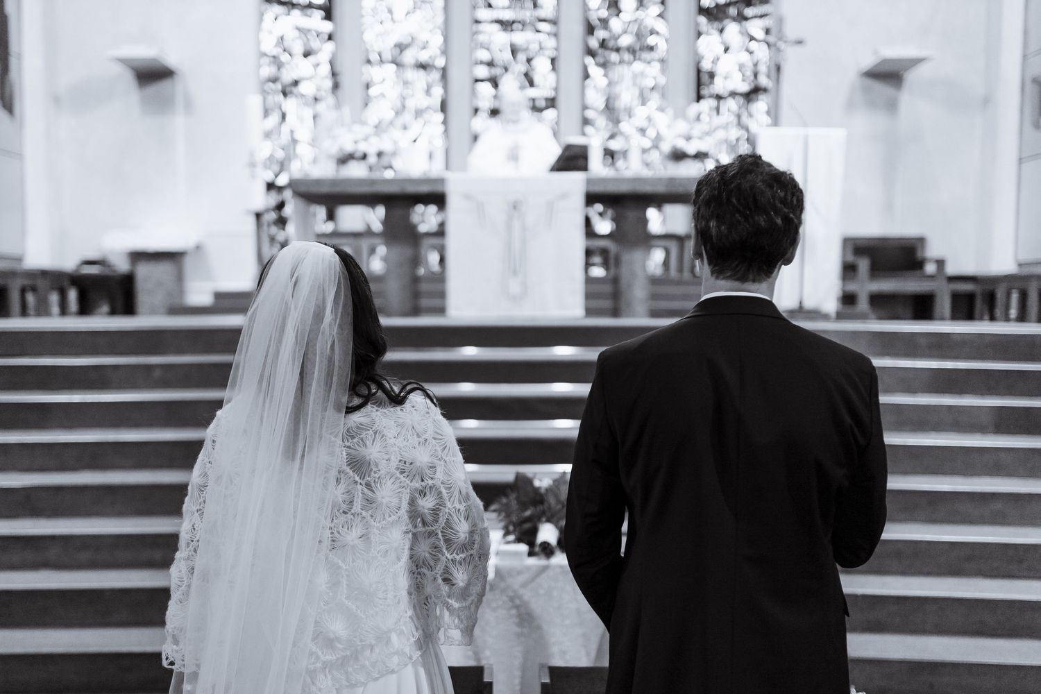 A black and white wedding photo montage showing multiple moments of a couple walking down church stairs.