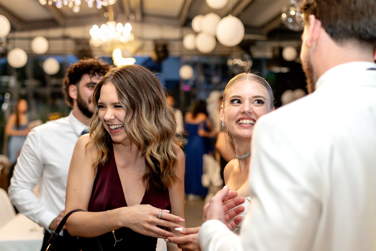 Wedding reception guests dance under chandelier and paper lantern lighting.