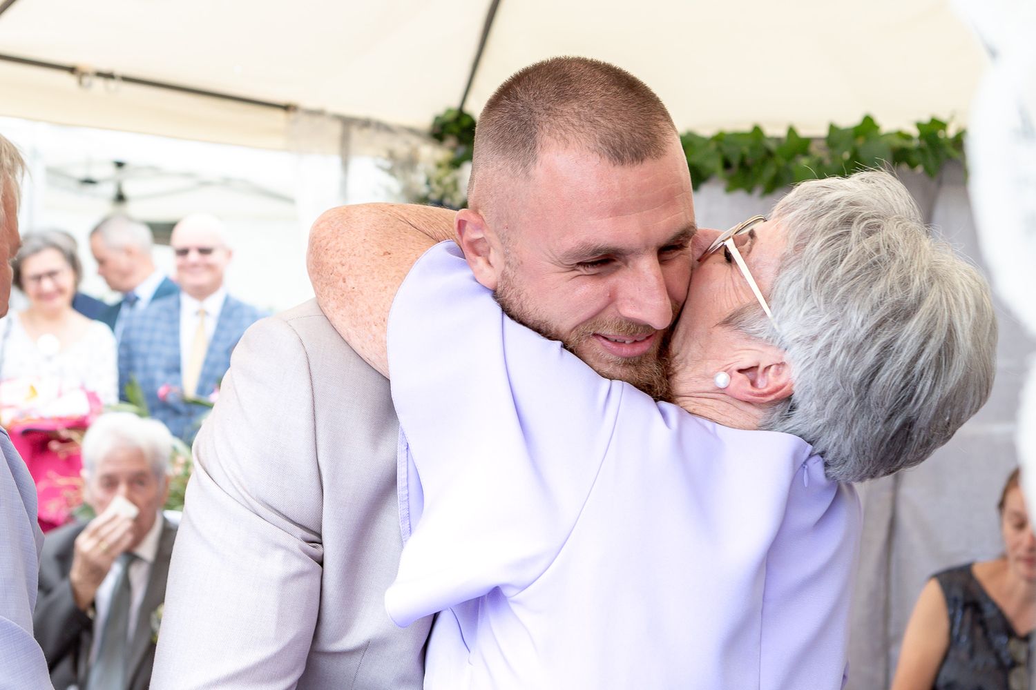 Wedding guests greet each other with warm embraces during an outdoor celebration.