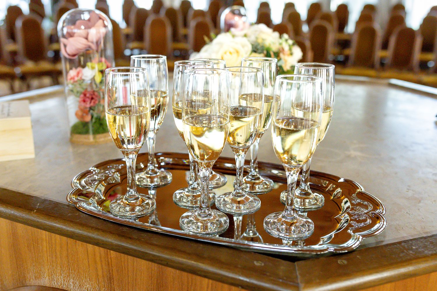 Crystal wine glasses arranged on silver serving trays at an elegant event setup.
