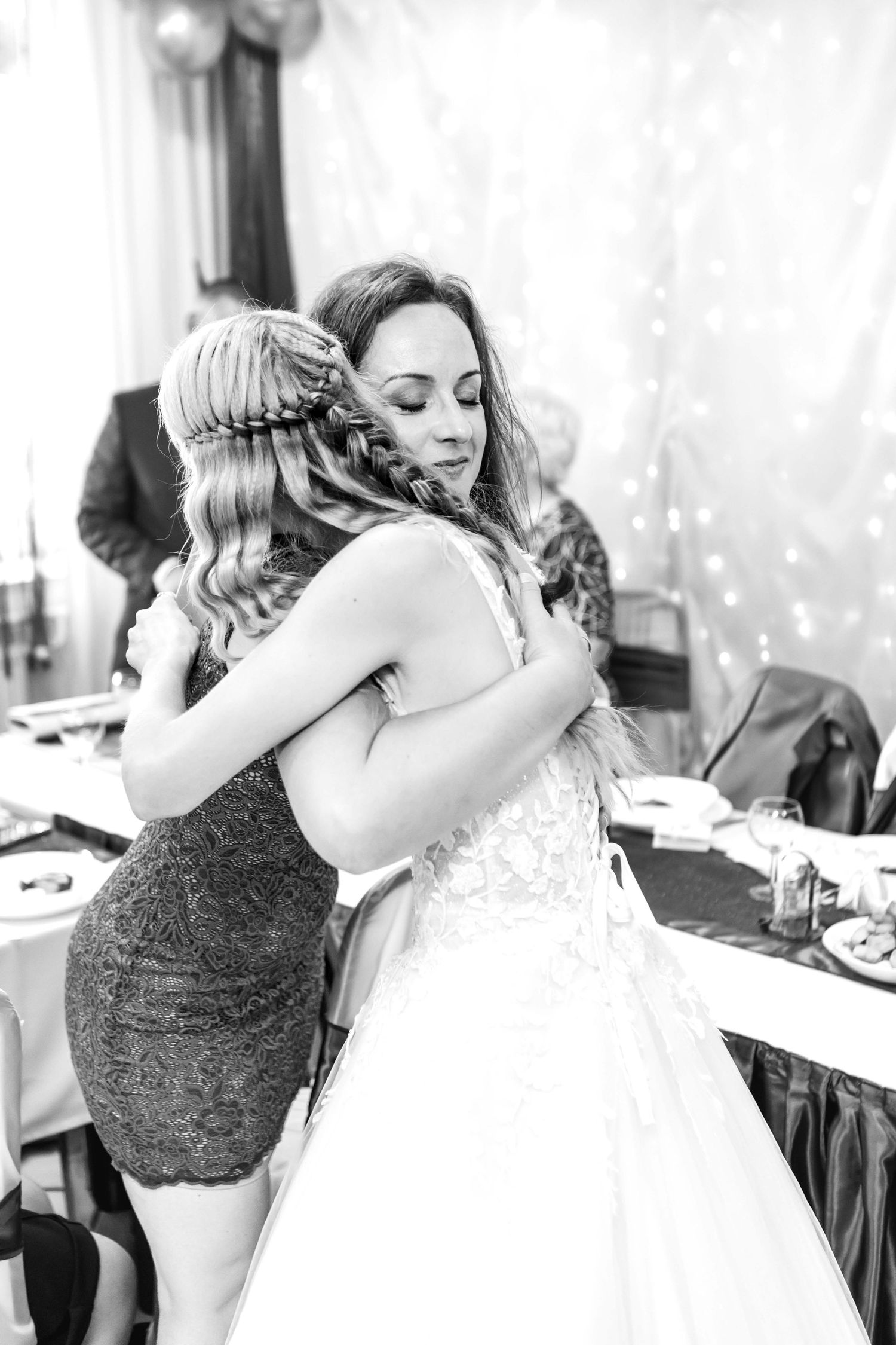 A heartfelt embrace between two women in formal attire at an elegant event.