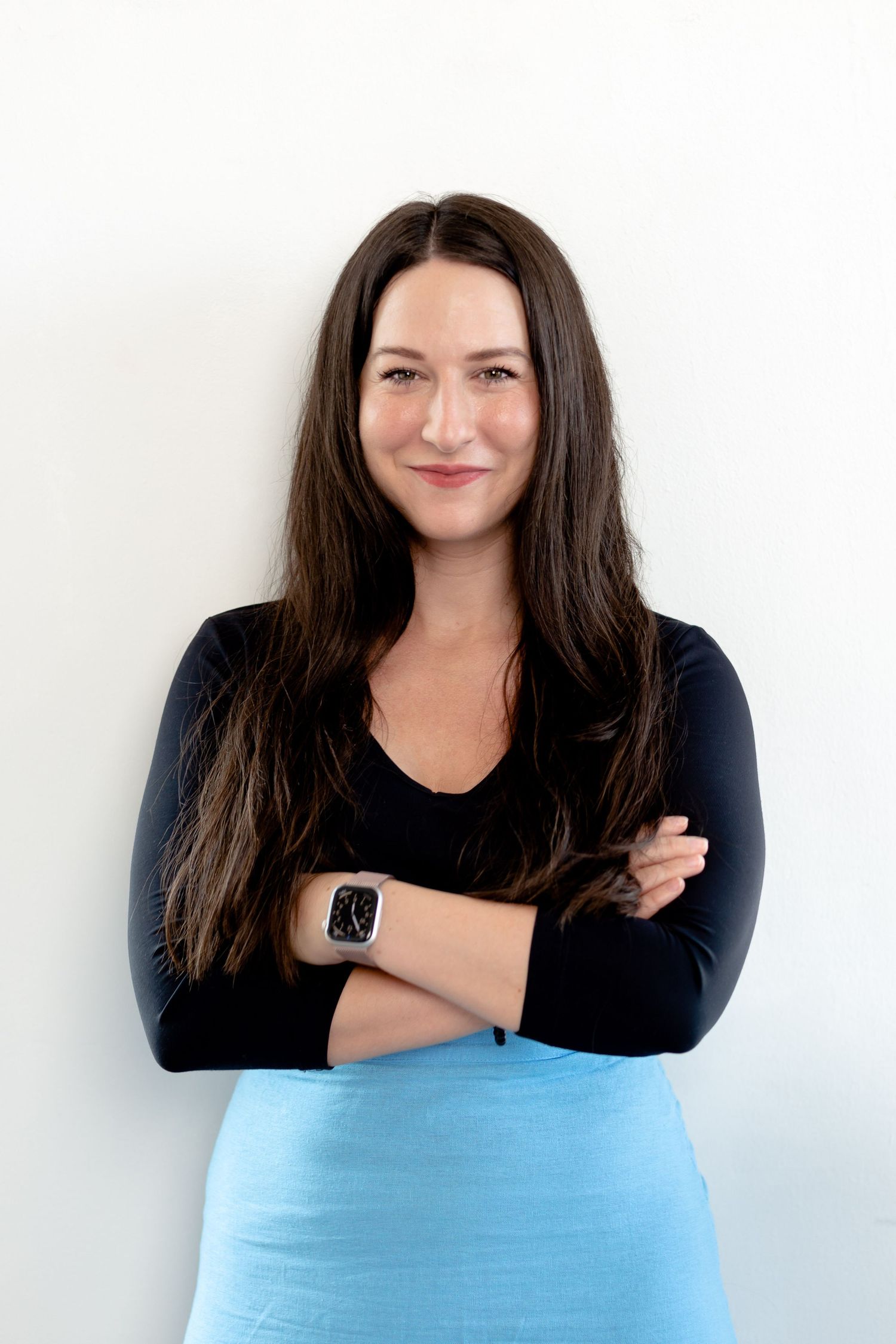 A person in dark attire and light blue clothing poses expressively against a white backdrop.