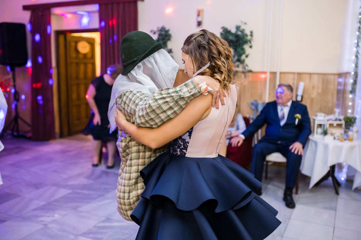 Couples dancing together at a wedding reception in a purple-lit ballroom.