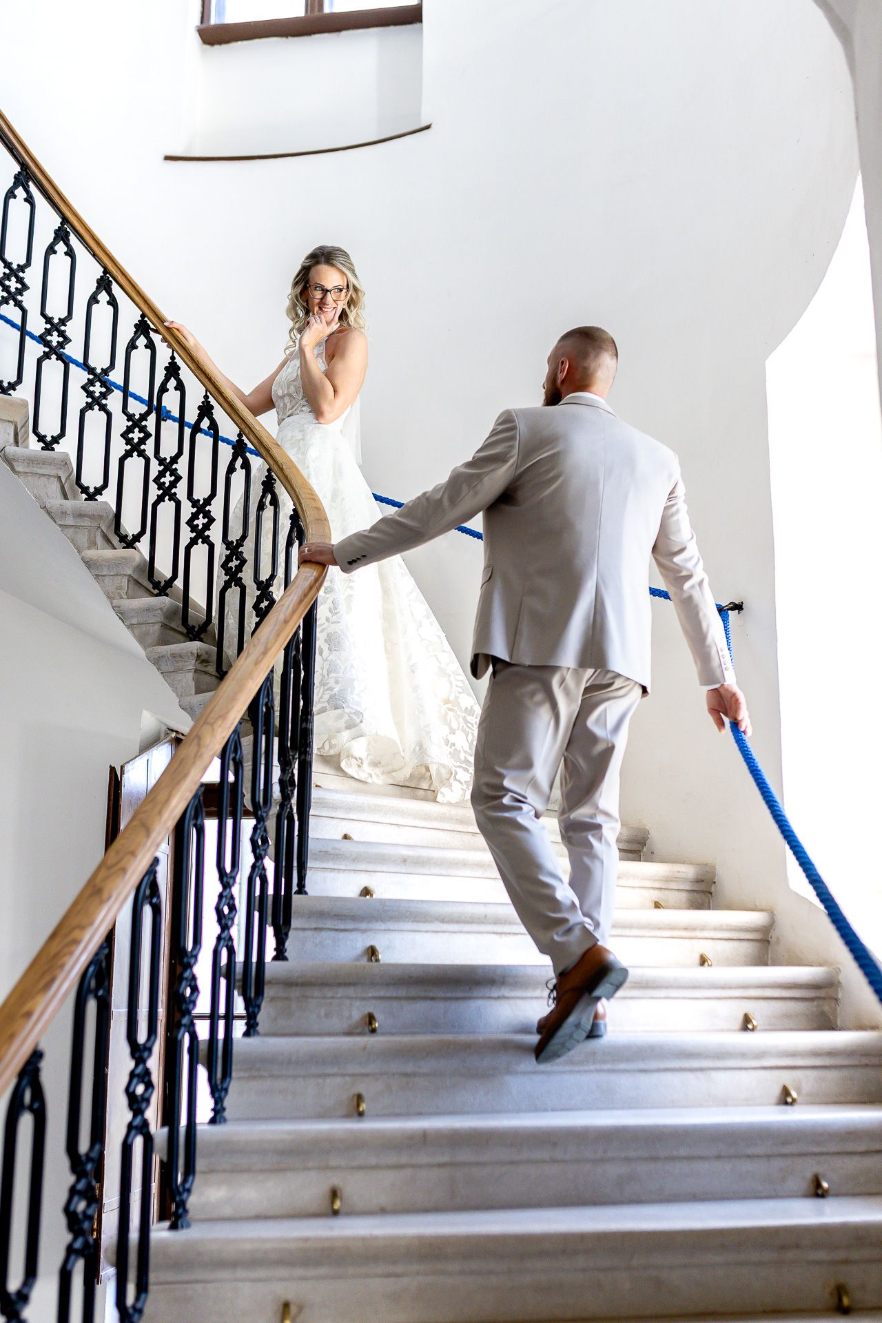 A series of photos showing someone in a gray suit ascending white marble stairs with an ornate black iron railing.
