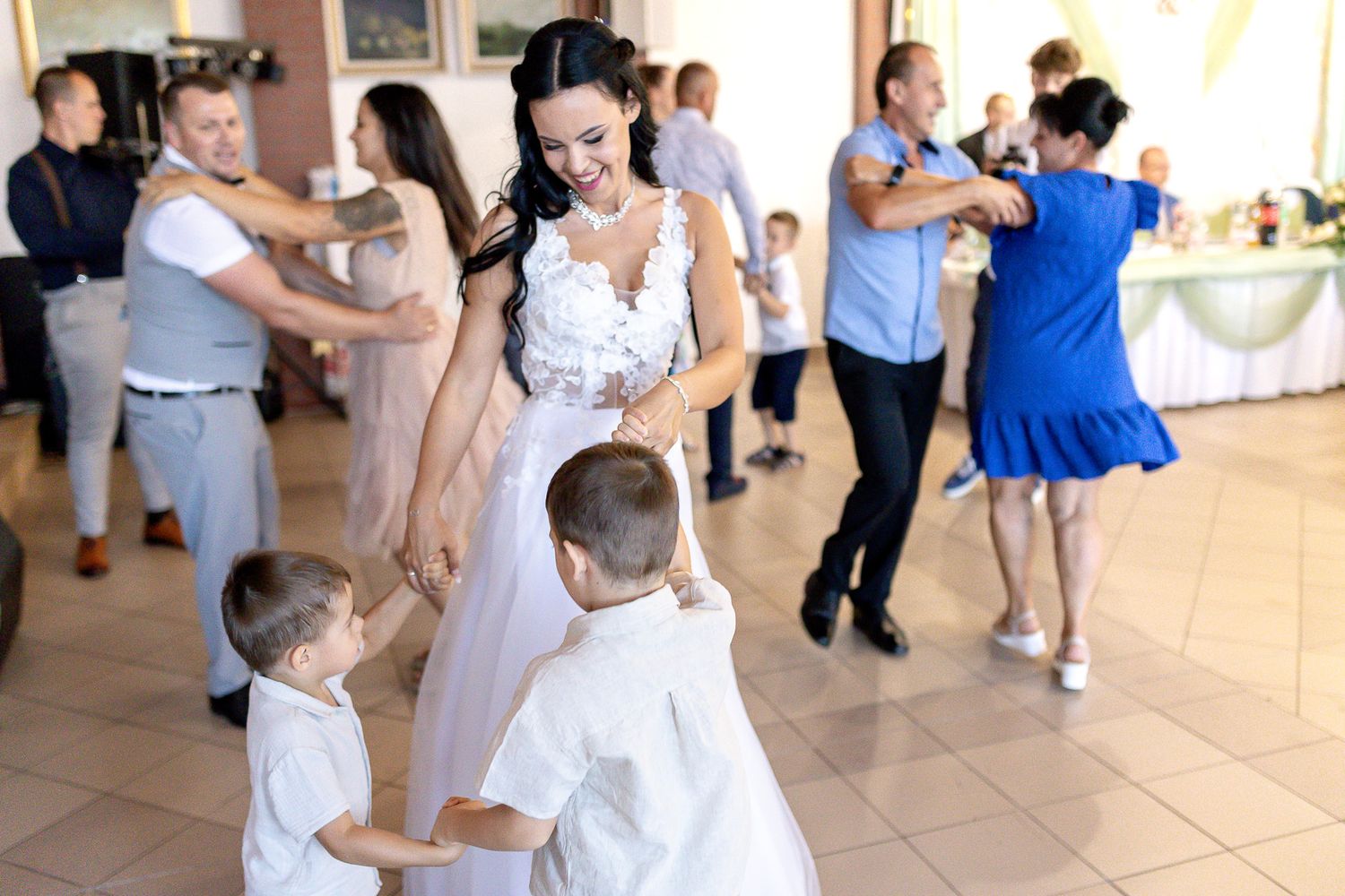 Couples dancing together in a bright ballroom during a formal event with white and blue attire.