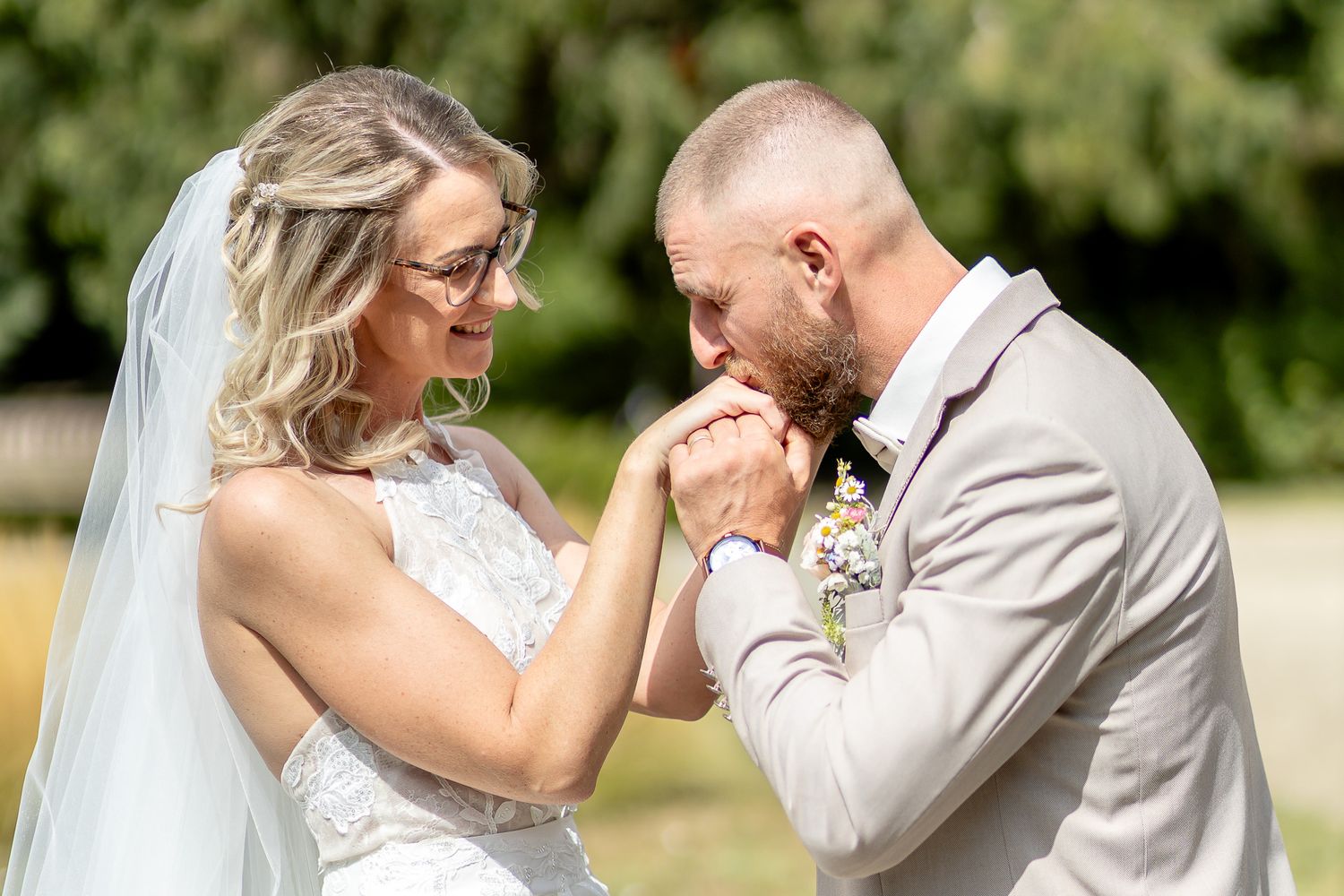 A tender moment between newlyweds outdoors as they share an emotional gesture in their wedding attire.