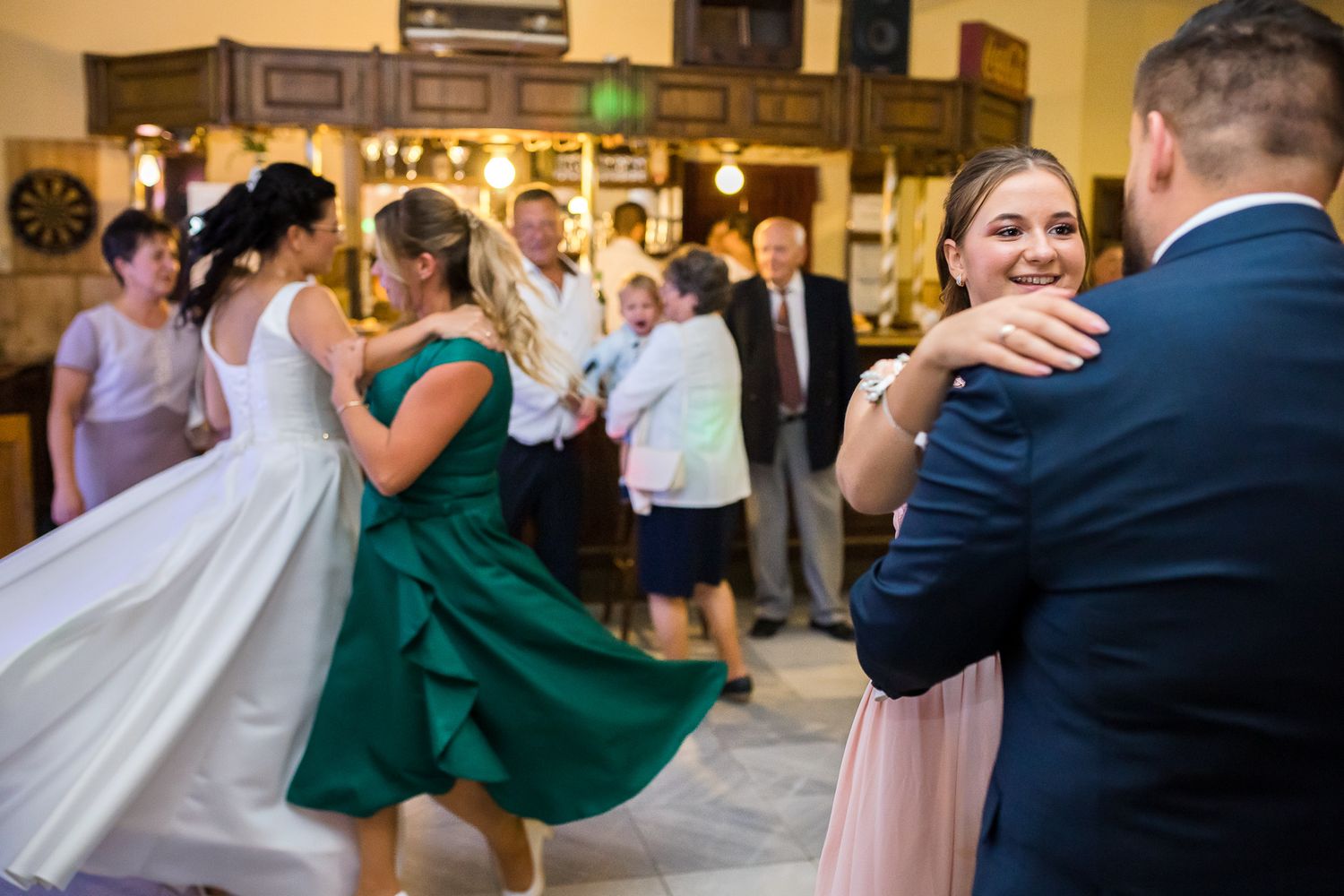 Wedding guests dance and twirl on the dance floor during an elegant reception celebration.