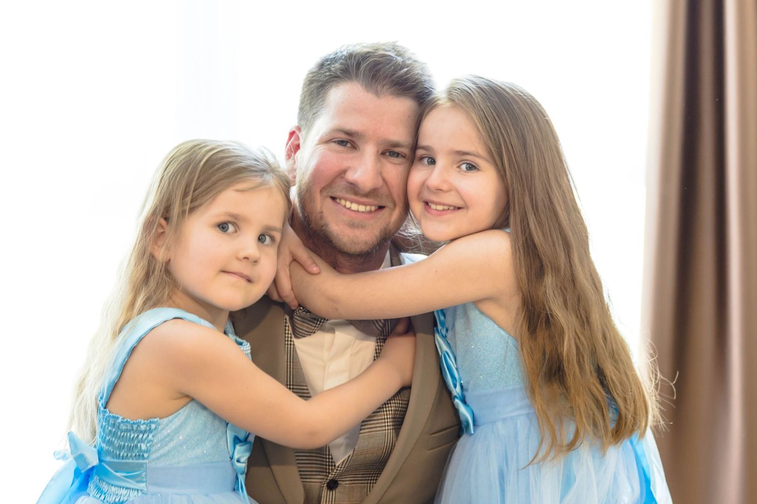 A family wearing casual clothing embraces and smiles together in a series of four connected photos.