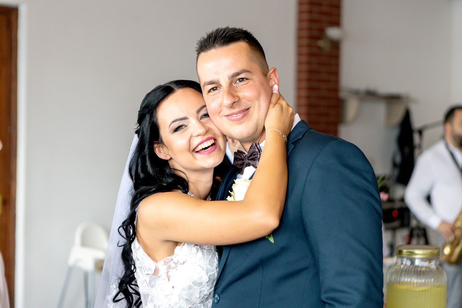 A joyful wedding celebration captured indoors with warm lighting and brick accents.