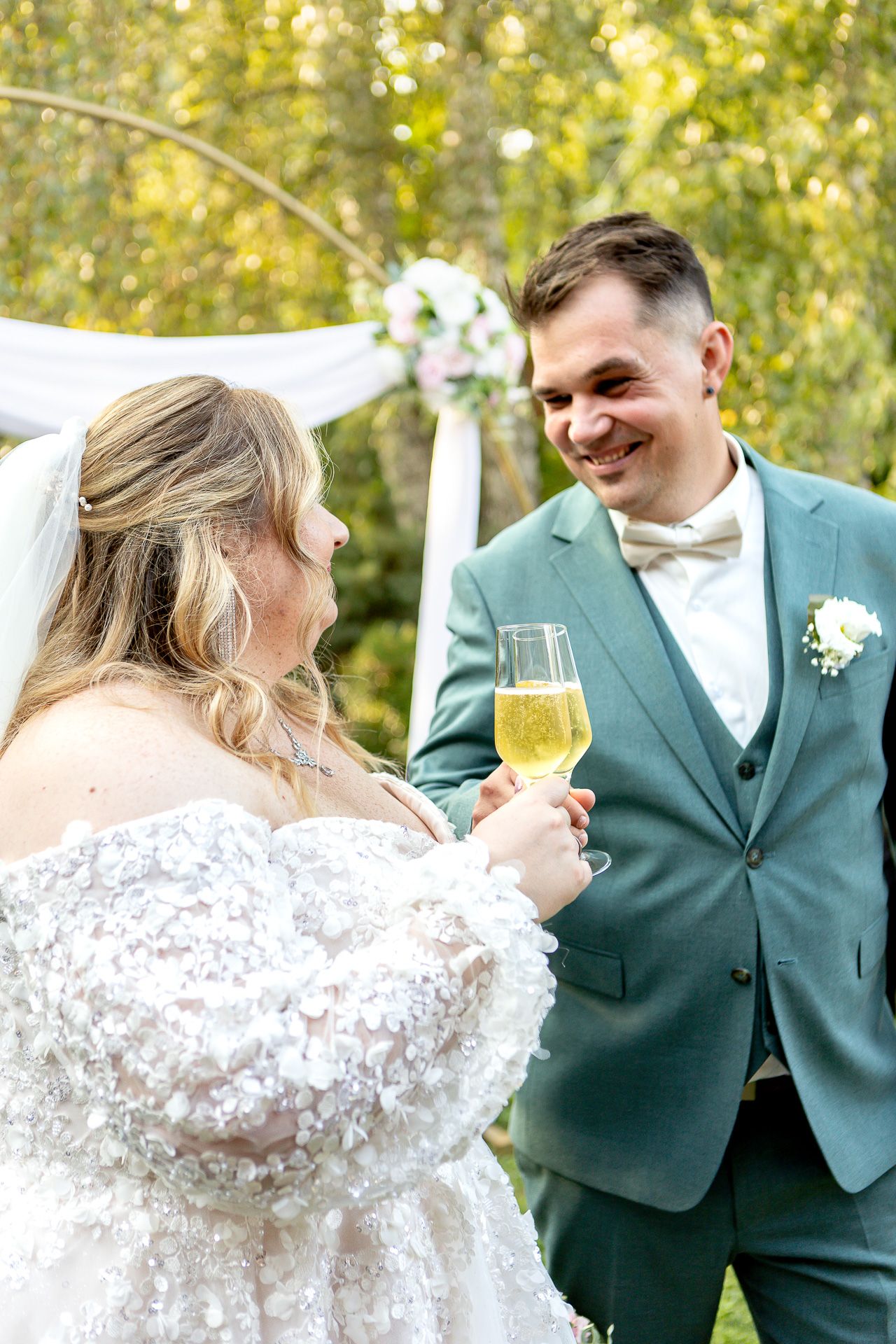 A bride and groom share joyful moments together outdoors with autumn foliage in the background.
