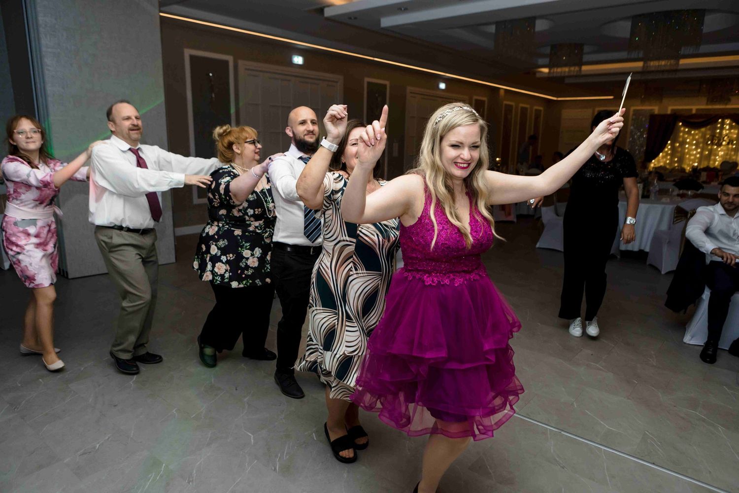 Dancers in purple dresses twirl and move energetically on a dance floor during a celebration.