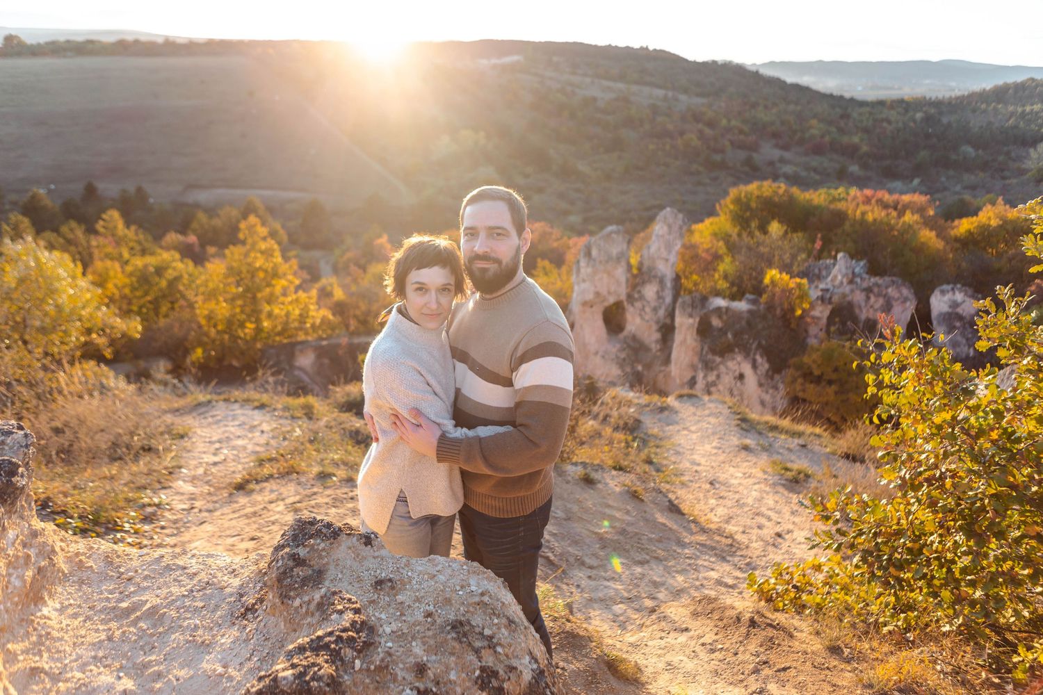 Intimate engagement photos captured at sunset with warm autumn colors in natural setting.
