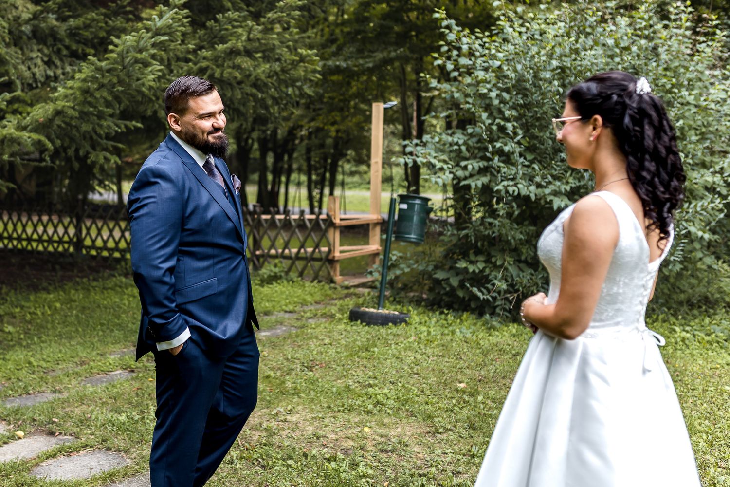 A couple in wedding attire shares a romantic moment in a lush garden setting during their special day.