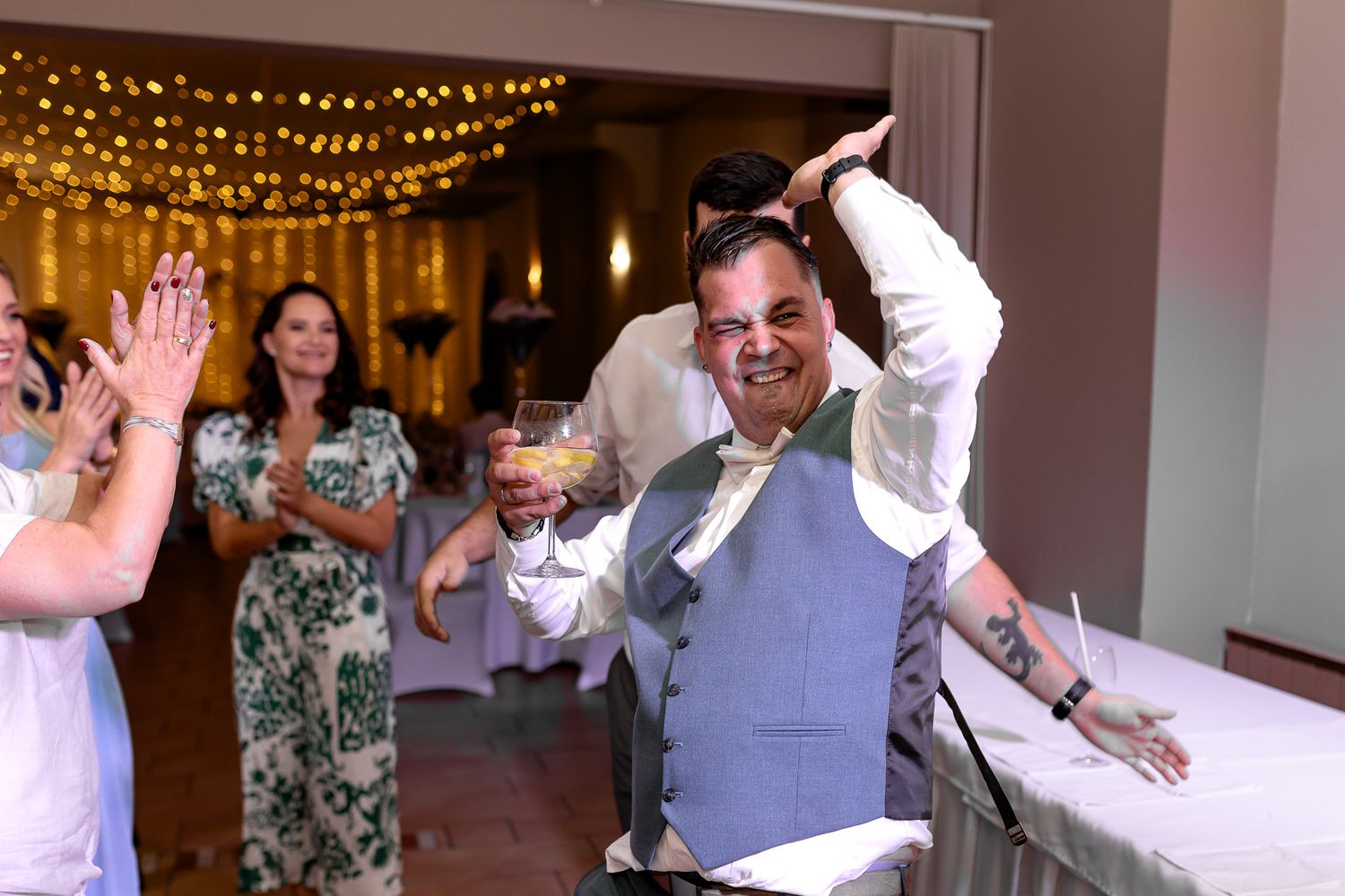 People dance and celebrate at a wedding reception with string lights decorating the venue.