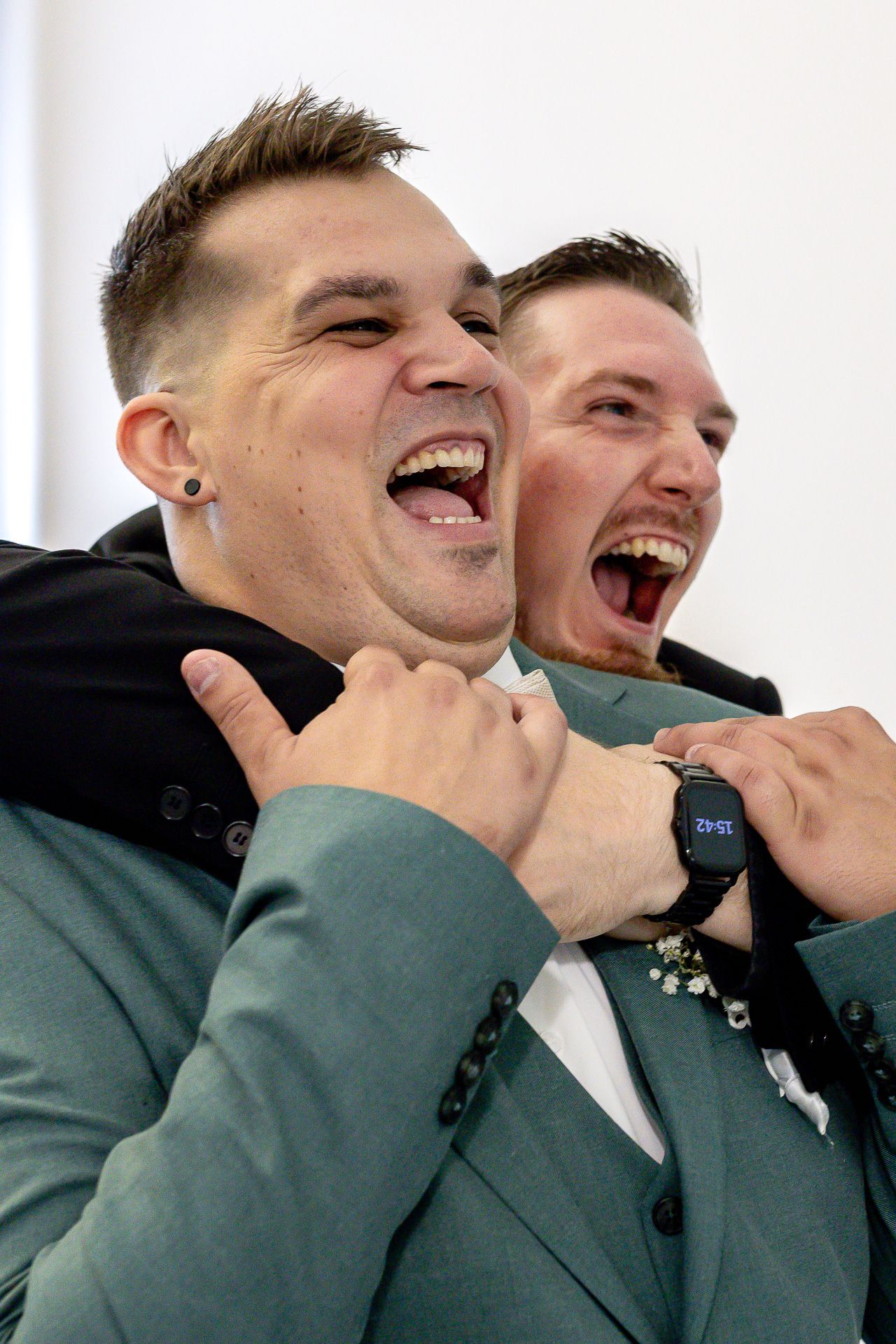 Two people in formal attire share a candid moment of laughter and joy during what appears to be a wedding celebration.