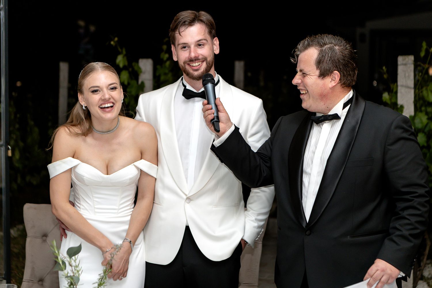 Wedding party members sharing laughs during formal reception celebrations.