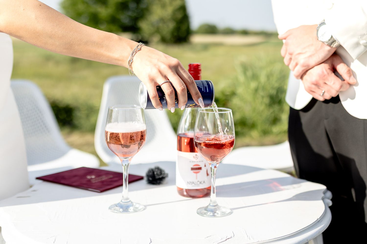 Wedding reception details with wine glasses and table settings in outdoor venue.