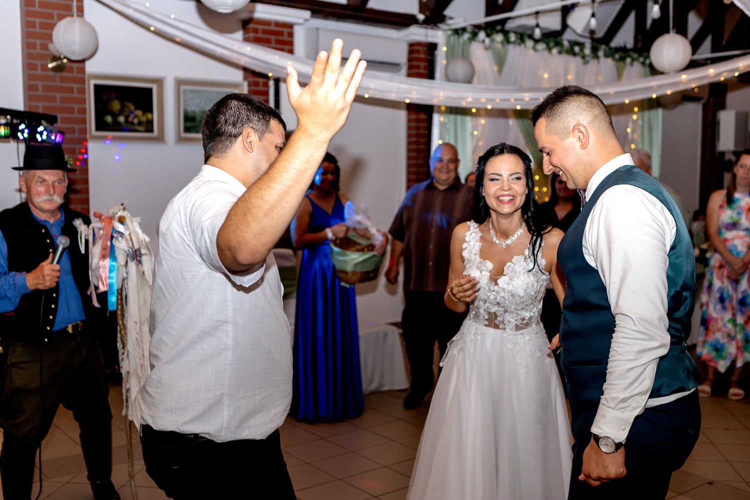 Wedding guests dance and celebrate together on a festively decorated dance floor at an indoor reception venue.