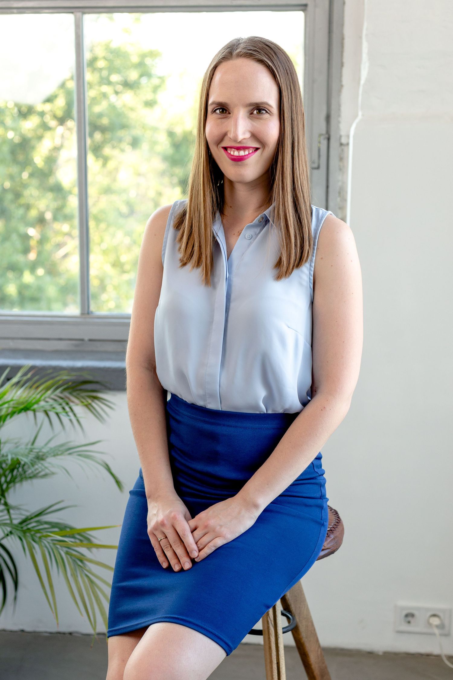 Professional headshots by a bright window with natural lighting and indoor plants.