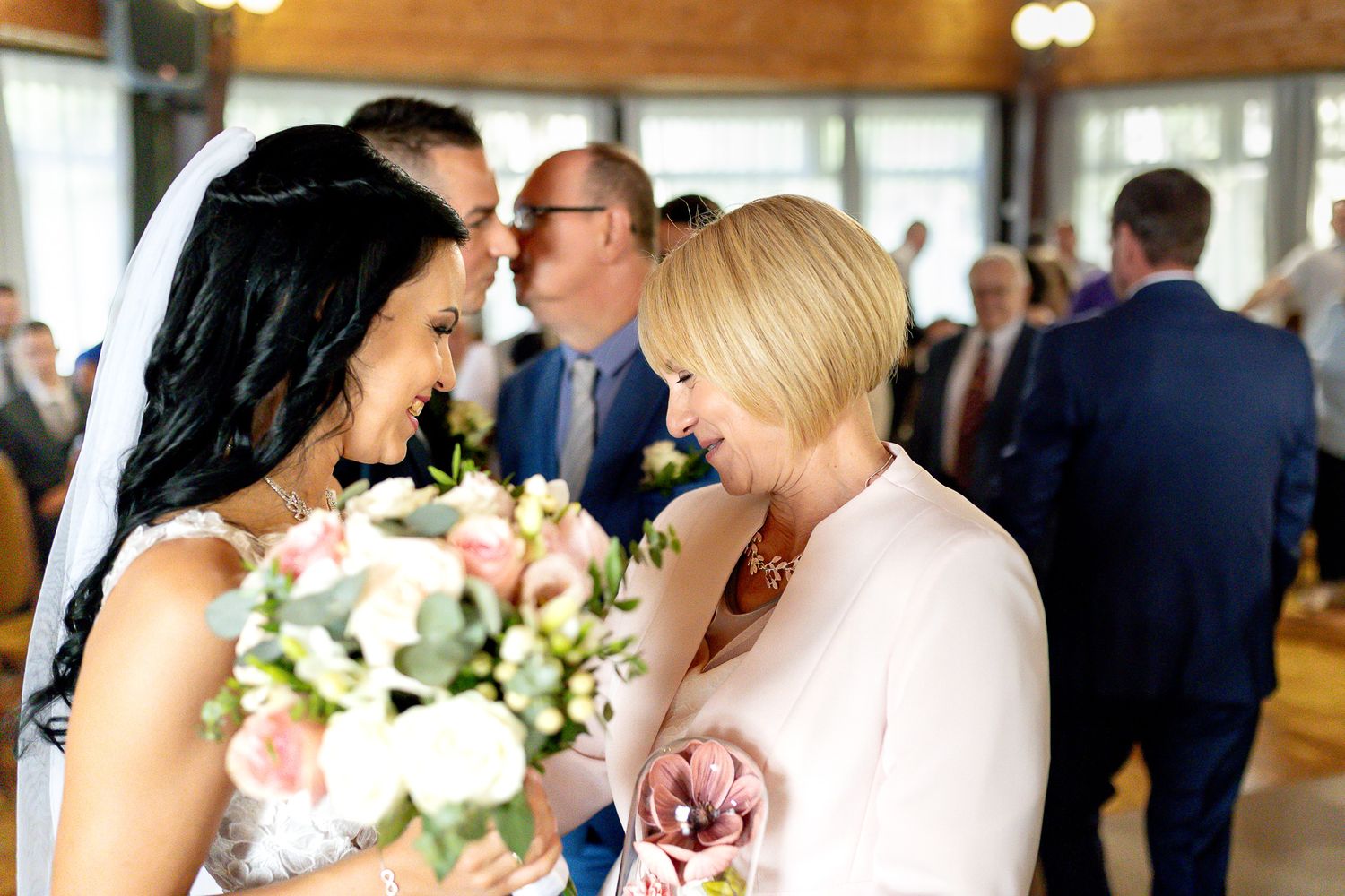 Wedding party members share joyful moments together during a celebration with floral bouquets and formal attire.