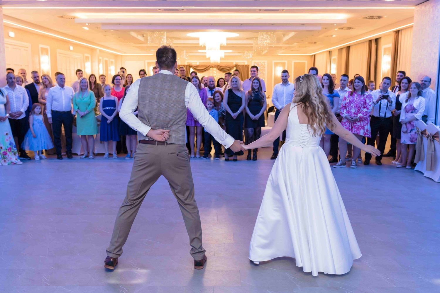 Wedding couple performs a synchronized dance move during their first dance in an elegant reception hall.