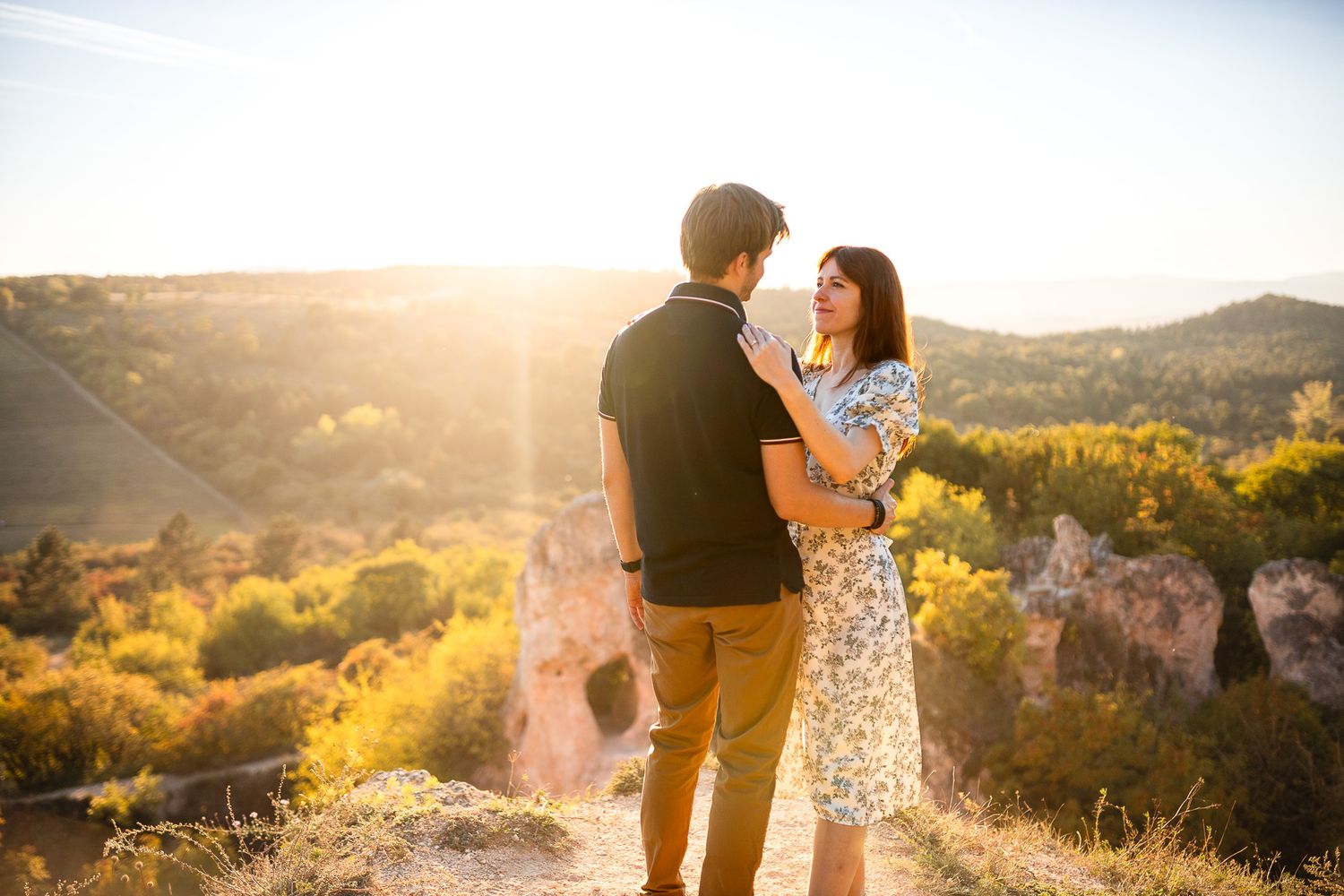 Romantic sunset photoshoot with couple on scenic mountain overlook.