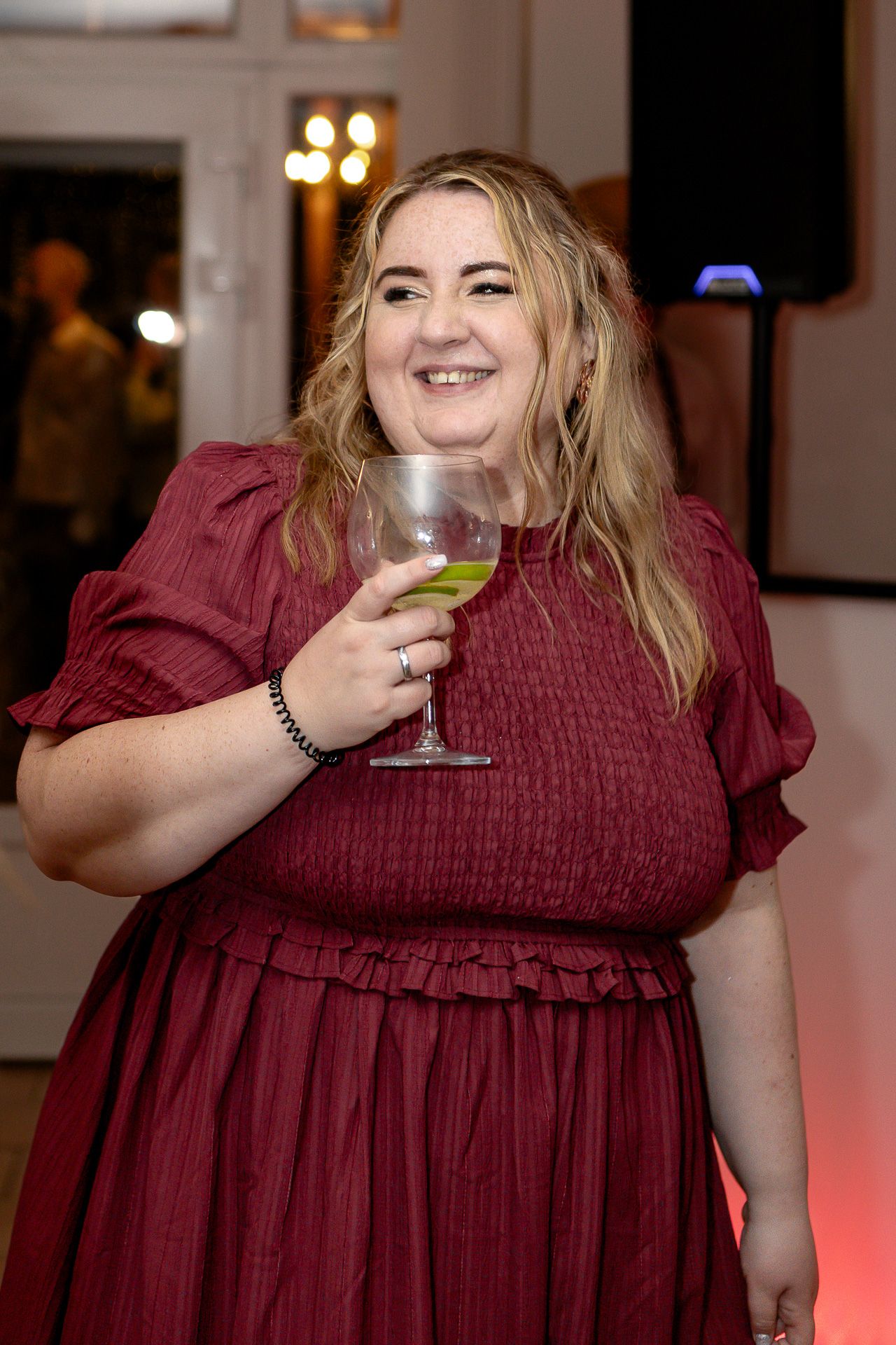 A sequence of photos shows someone in a burgundy dress holding and sipping from a glass of wine.