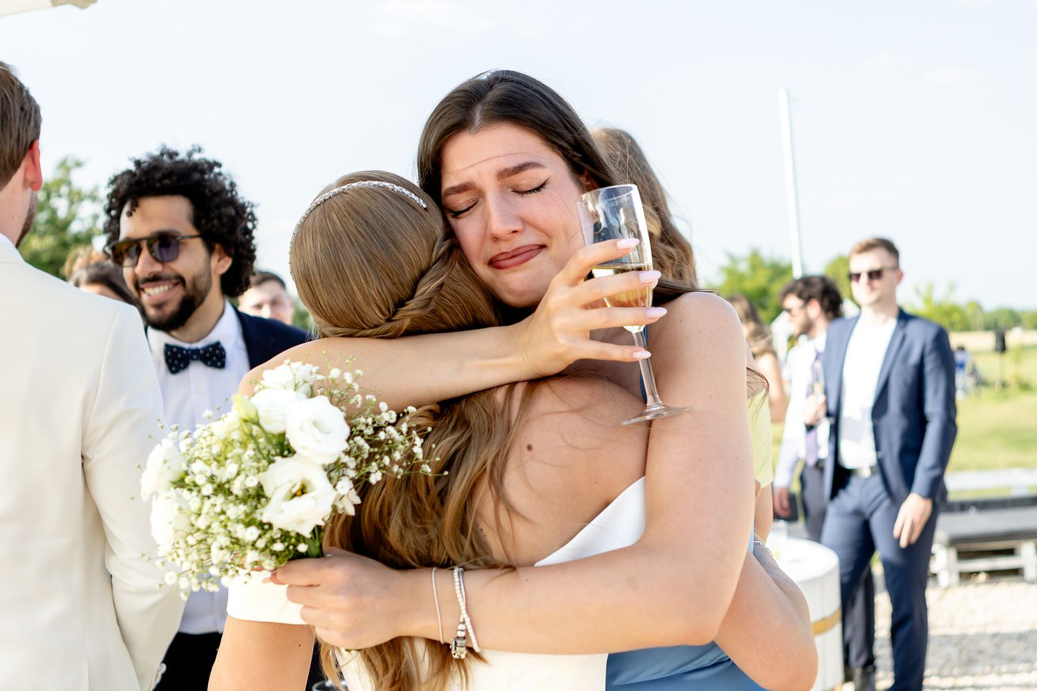 Guests share heartfelt hugs and embraces during outdoor wedding reception.