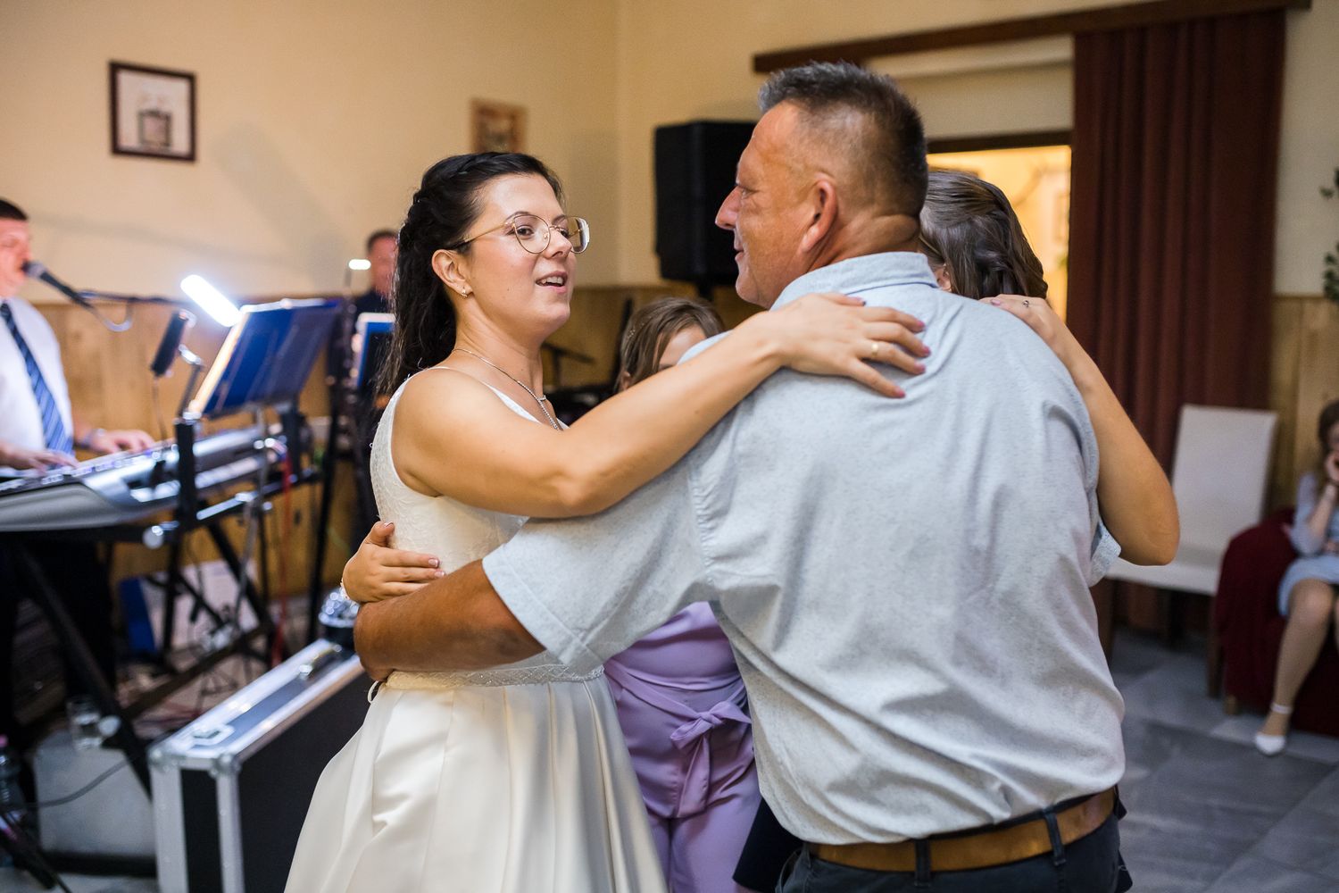 A couple dancing together in an indoor venue with other dancers visible in the background.