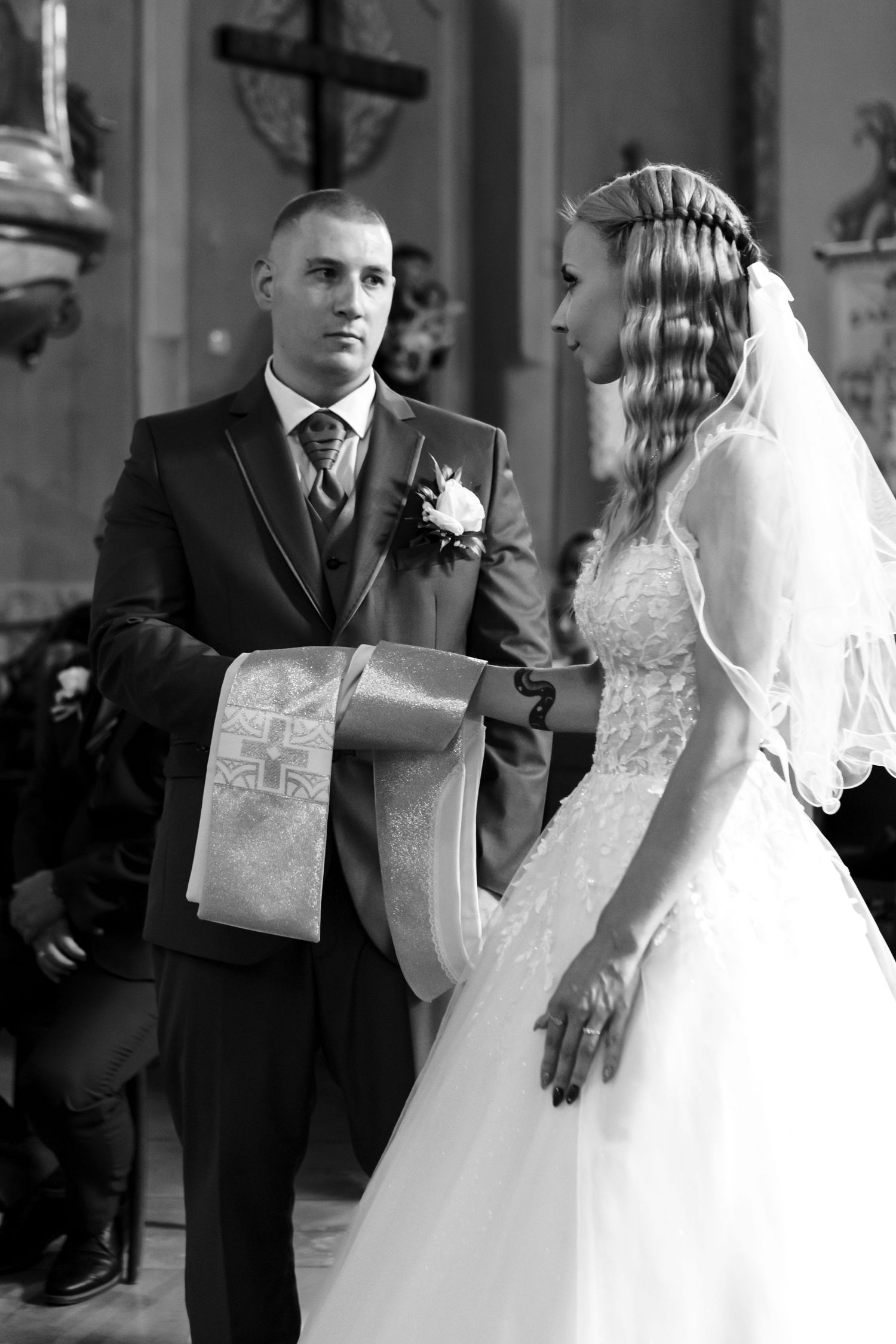 A black and white photo of a wedding ceremony in a church with a couple standing at the altar.