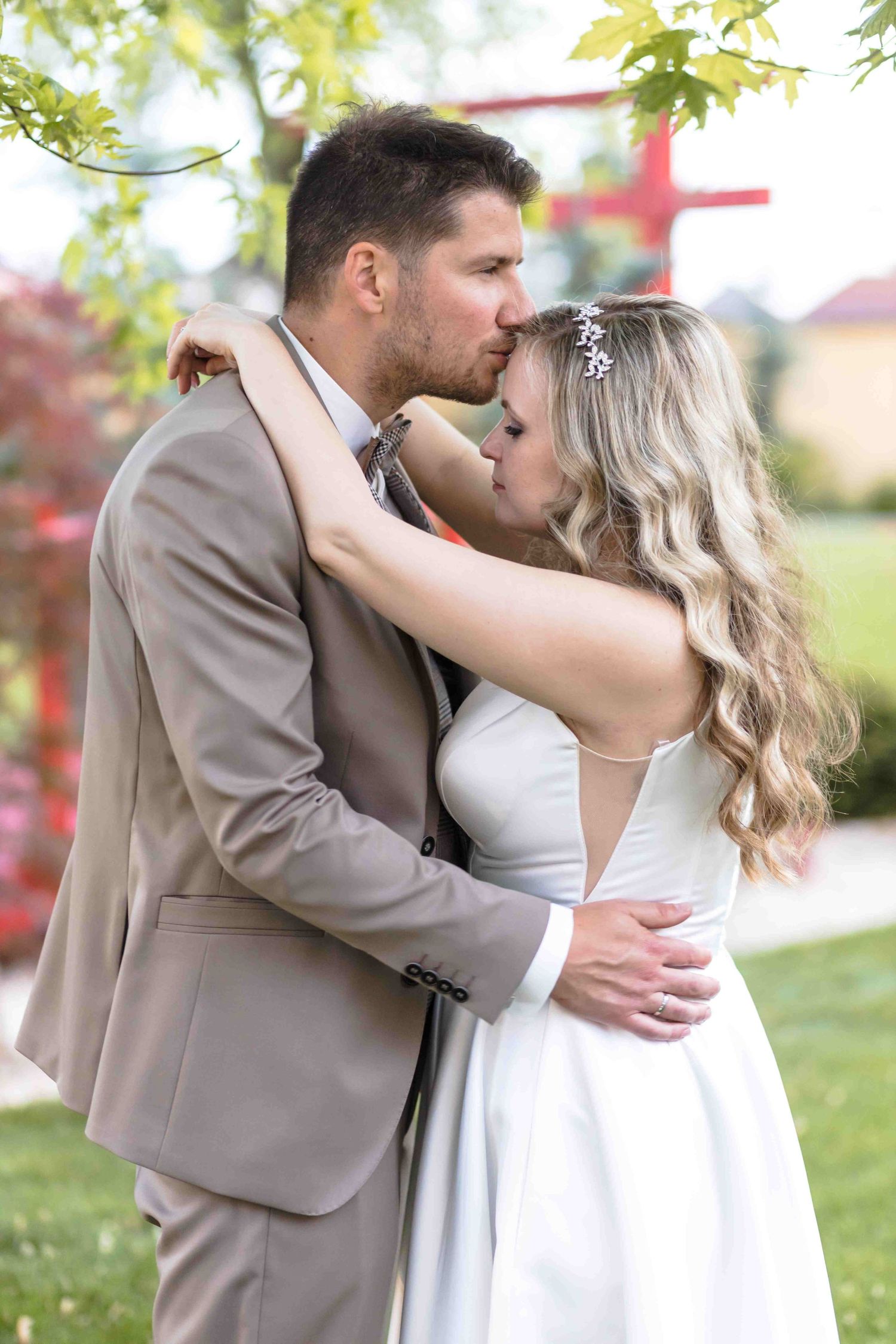 A romantic wedding couple shares intimate moments in a garden setting with soft natural lighting and greenery.