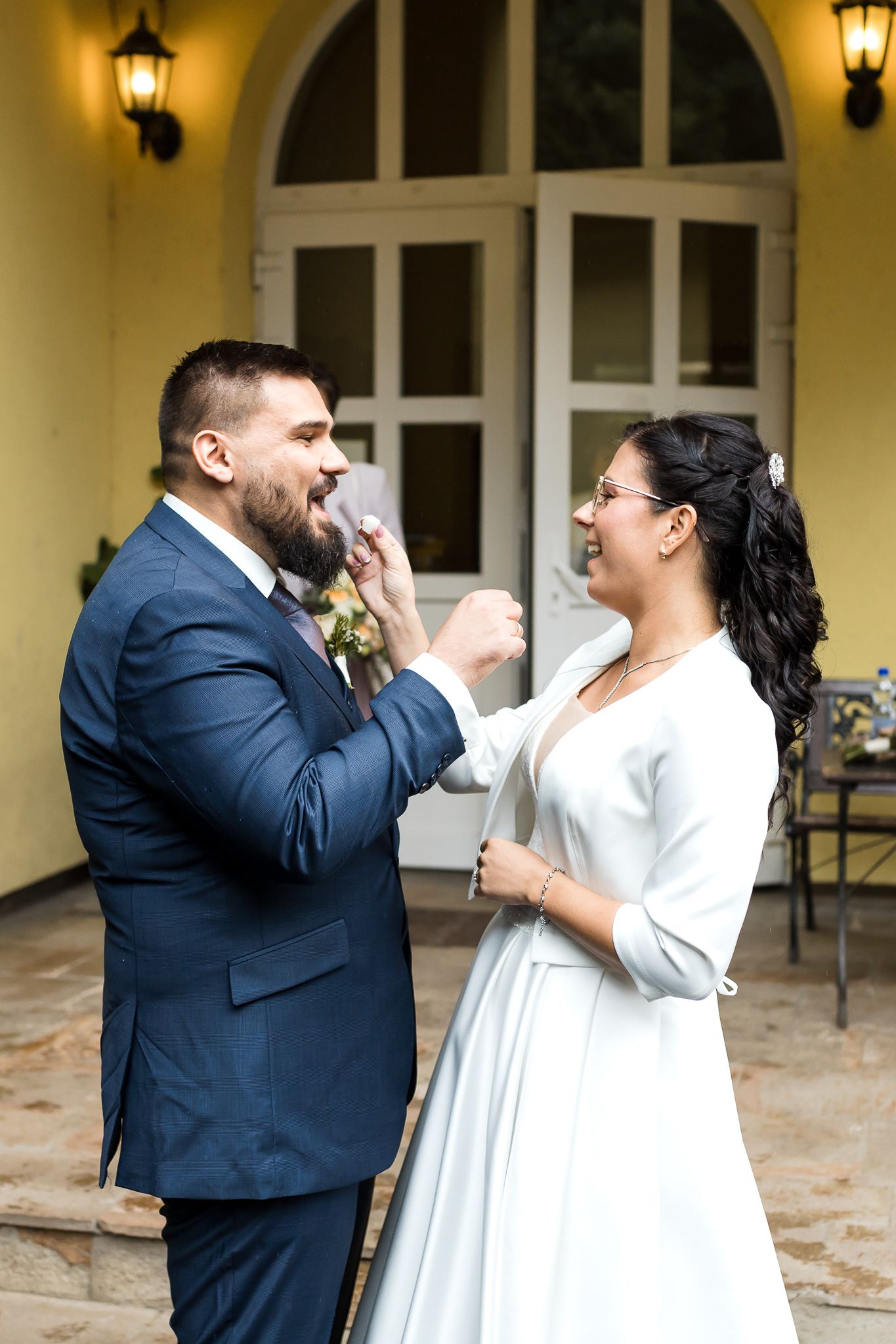 A couple in wedding attire sharing a tender dance moment on a covered patio with lanterns in the background.