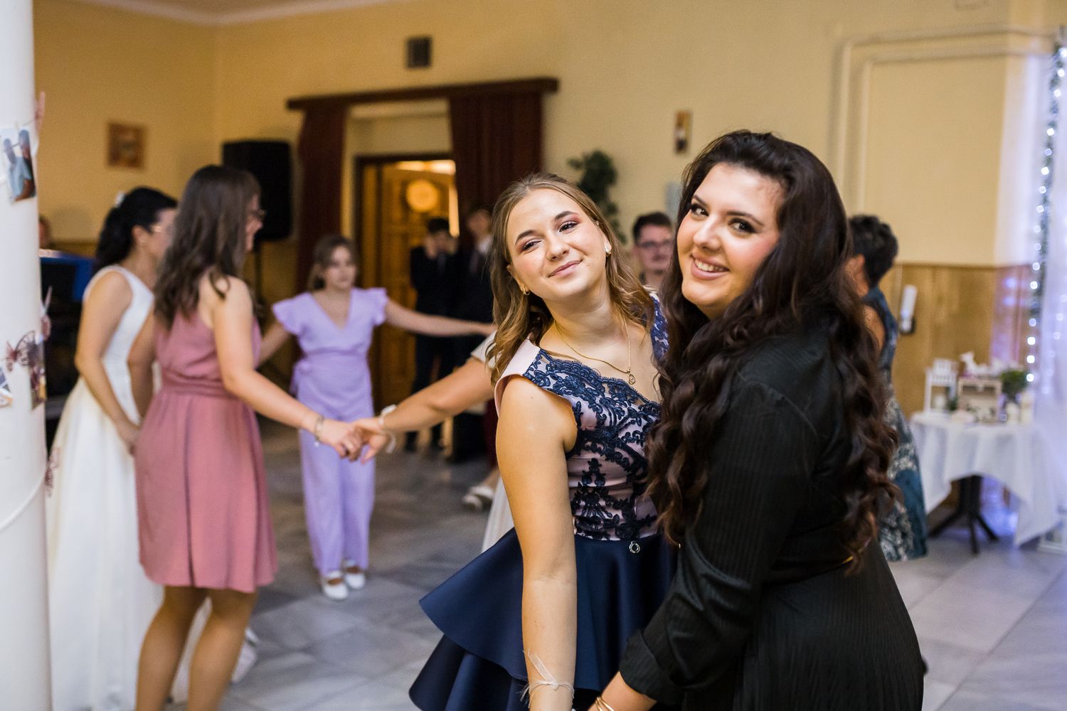 Wedding guests dancing and celebrating together on the dance floor at an indoor reception venue.