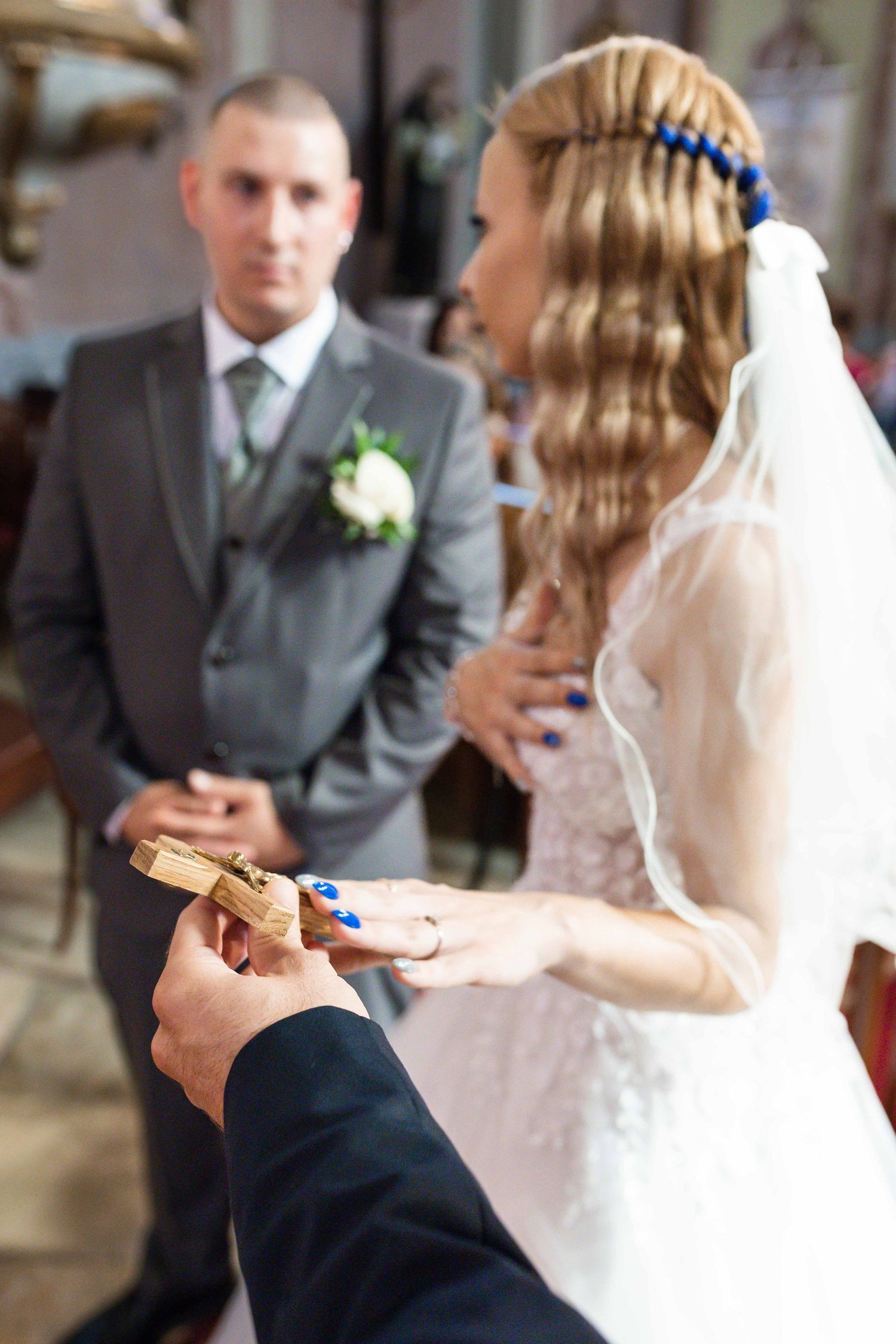 Close-up of hands exchanging wedding rings during an indoor ceremony.