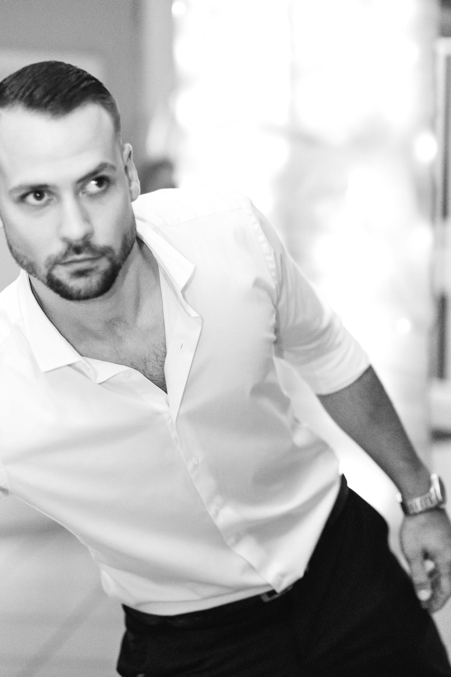 A black and white portrait shows someone in a white shirt smiling and looking to the side with a playful expression.