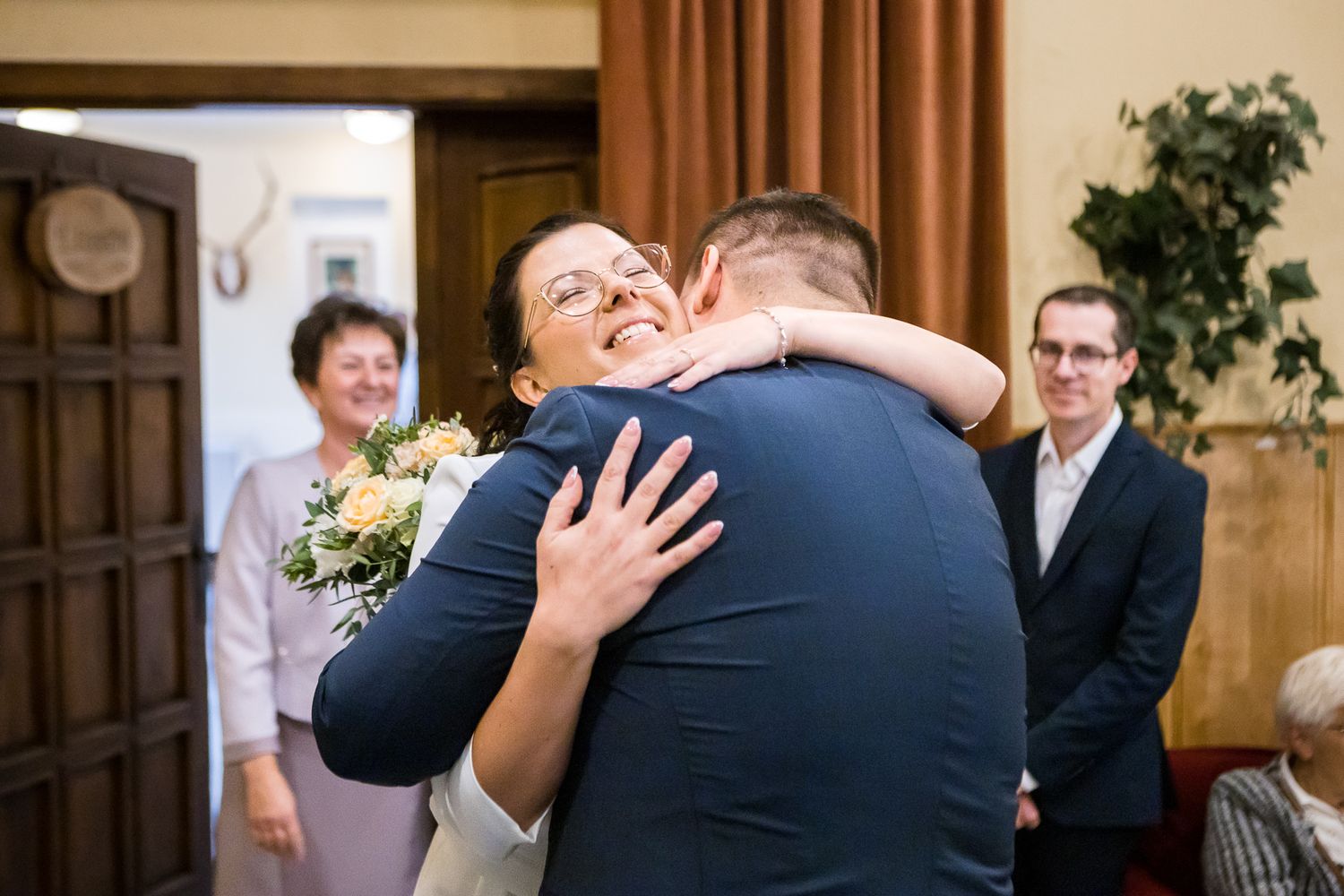 A sequence of candid wedding moments showing joyful reactions and embraces during an indoor celebration.